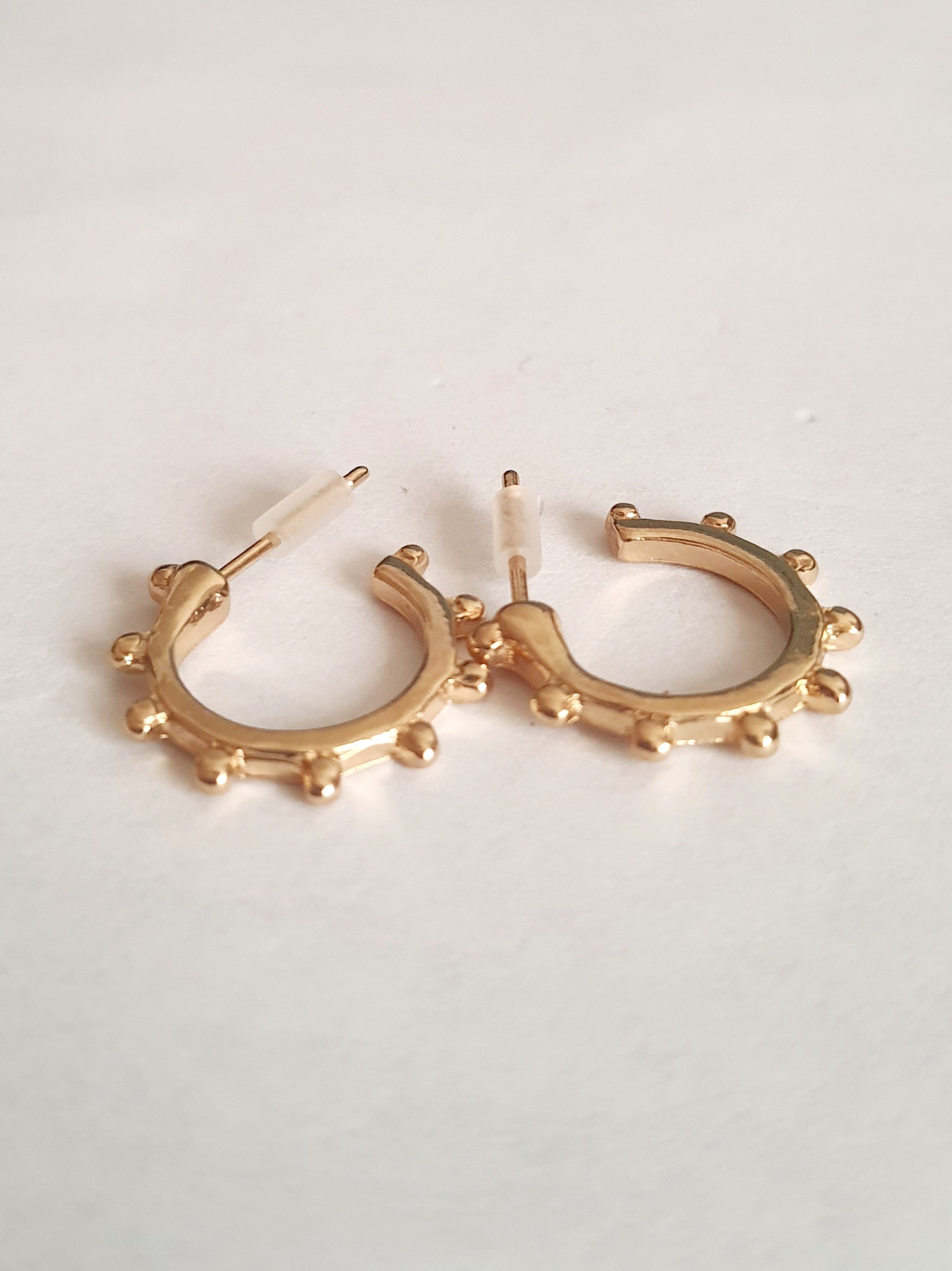 Zestaw 3 par złotych kolczyków typu kółka: kolorowe cyrkonie (1,5 cm), wypustki (1,5 cm), klasyczne z cyrkonią (1 cm). Zapięcie na sztyft. Rouge bizu