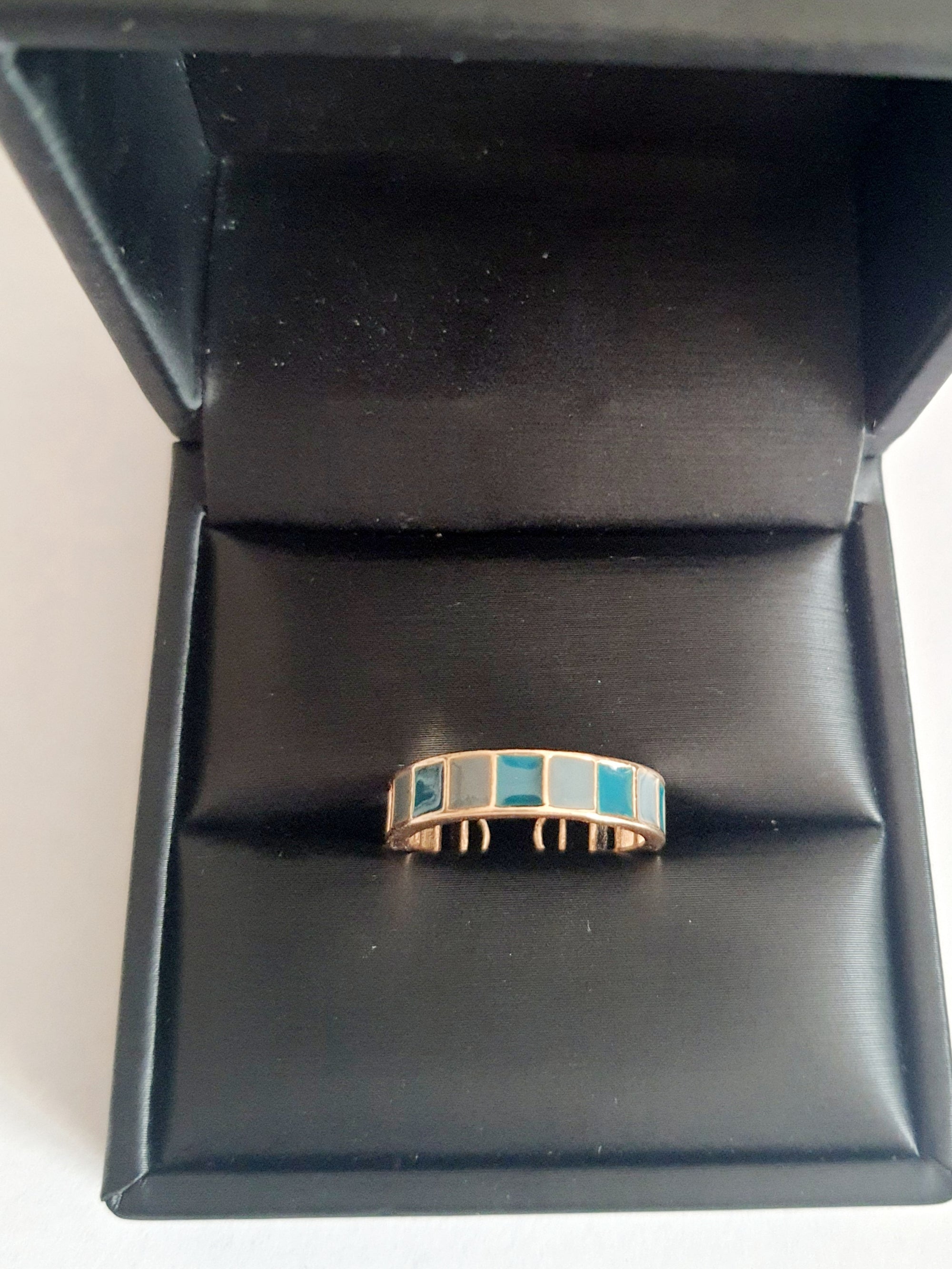 Pierścionek ze stali nierdzewnej z niebieskimi prostokątnymi emaliowanymi segmentami. Styl nowoczesny, minimalistyczny, art deco. Rozmiar 16 mm, otwarty. Geometryczny wzór w odcieniach błękitu. RougeBizu.


