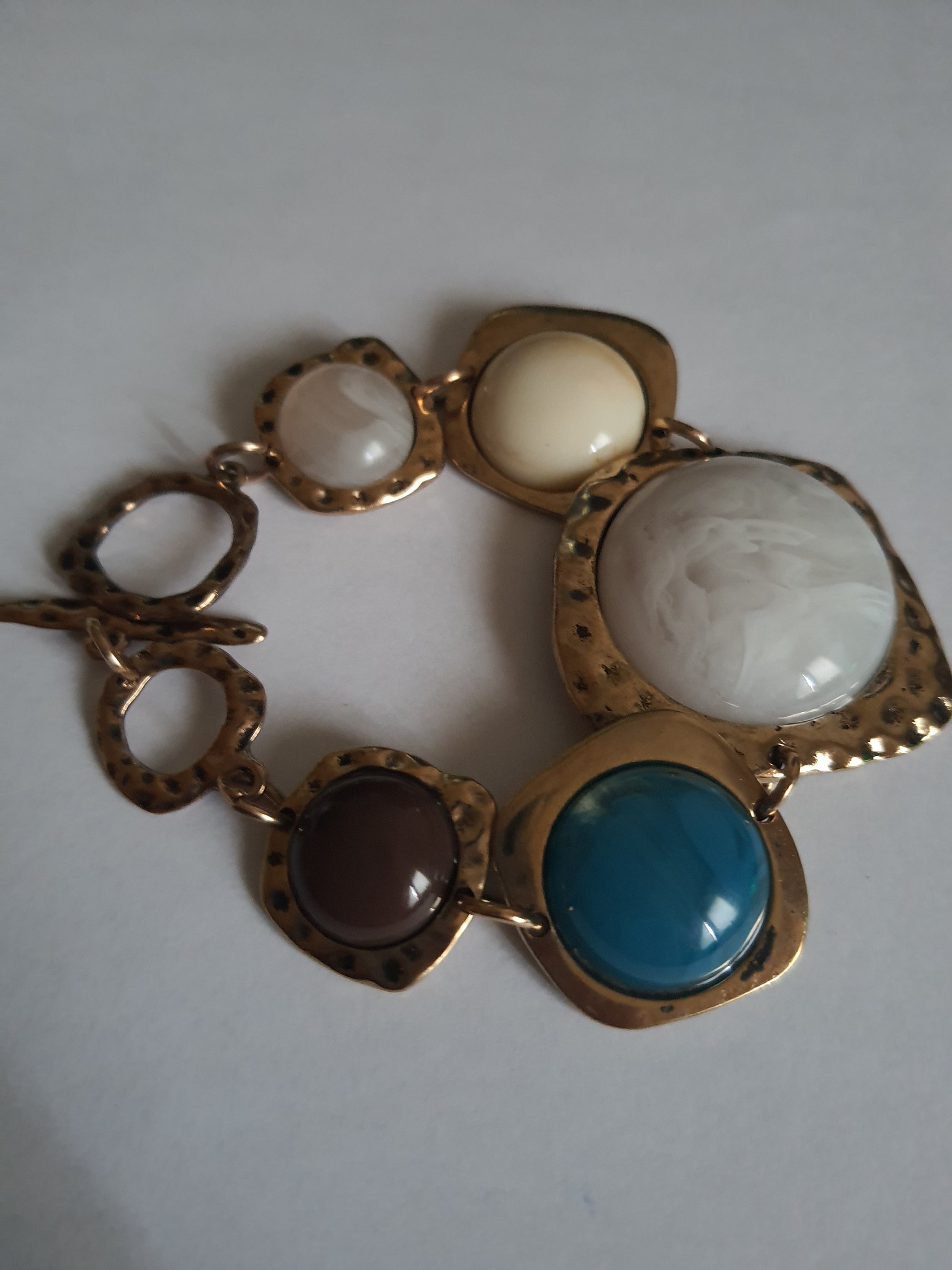 Artystyczna bransoletka damska z medalionami w kolorach marmuru, niebieskiego i brązu w nieregularnych złotych ramkach. Długość 20 cm. Styl boho, wyrazisty design. Stal nierdzewna, stal chirurgiczna. Rouge Bizu.

