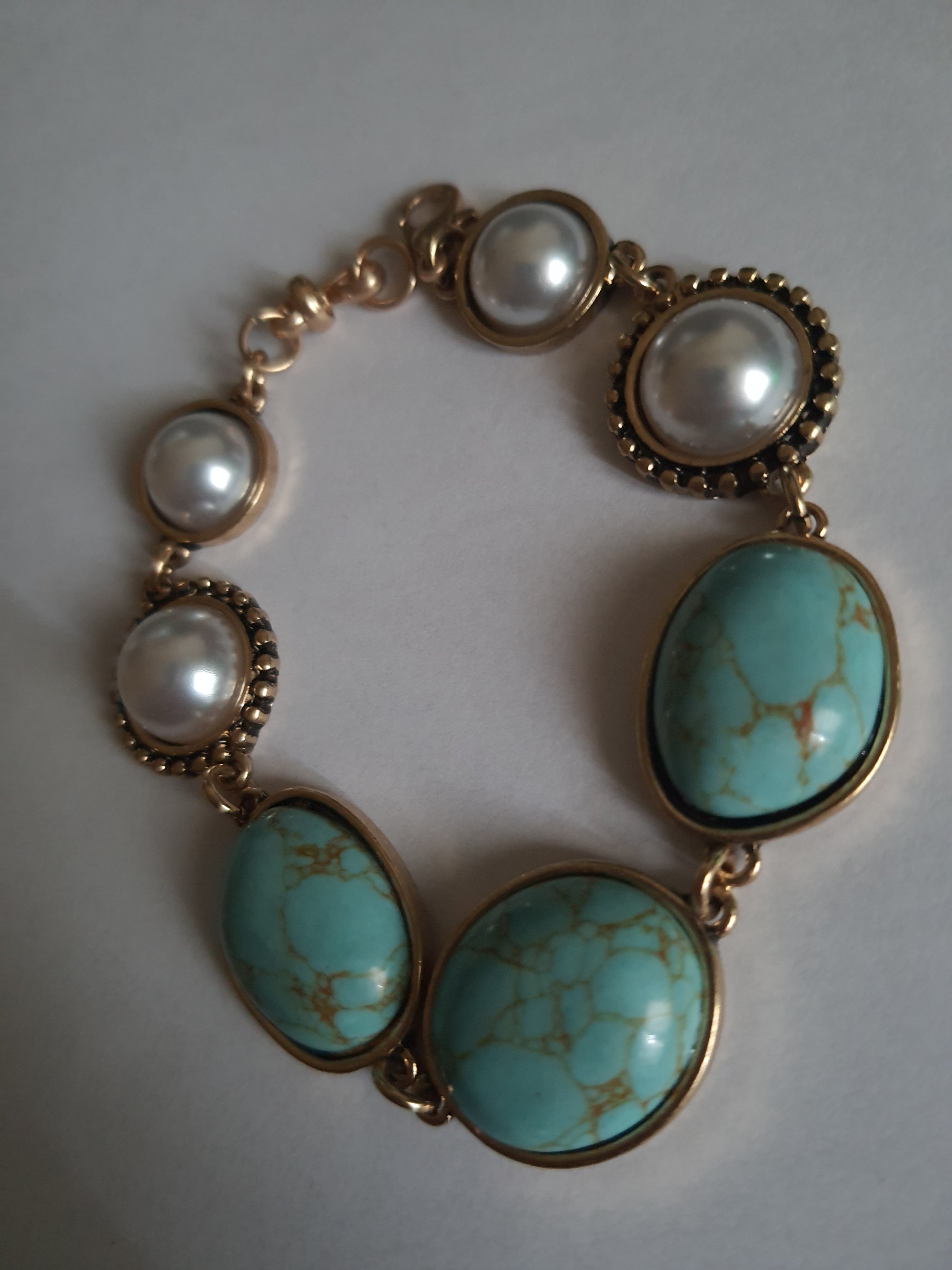 Bransoletka w stylu vintage ze złotą oprawą, ozdobiona turkusowymi kamieniami i perłami. Długość 20 cm. Klasyczna, elegancka forma. Biżuteria ze stali nierdzewnej. Rouge Bizu.

