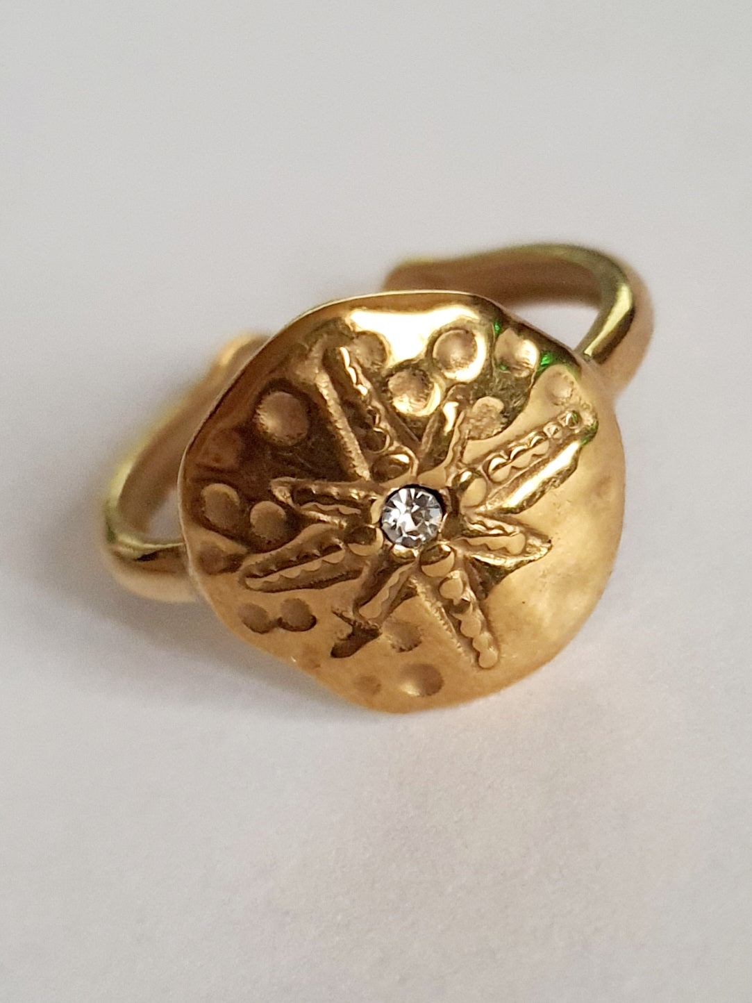 Złoty pierścionek regulowany, rozmiar 19 mm, z motywem tłoczonej gwiazdy morskiej i centralną cyrkonią. Styl boho i vintage, stal nierdzewna, stal chirurgiczna. Rouge Bizu.

