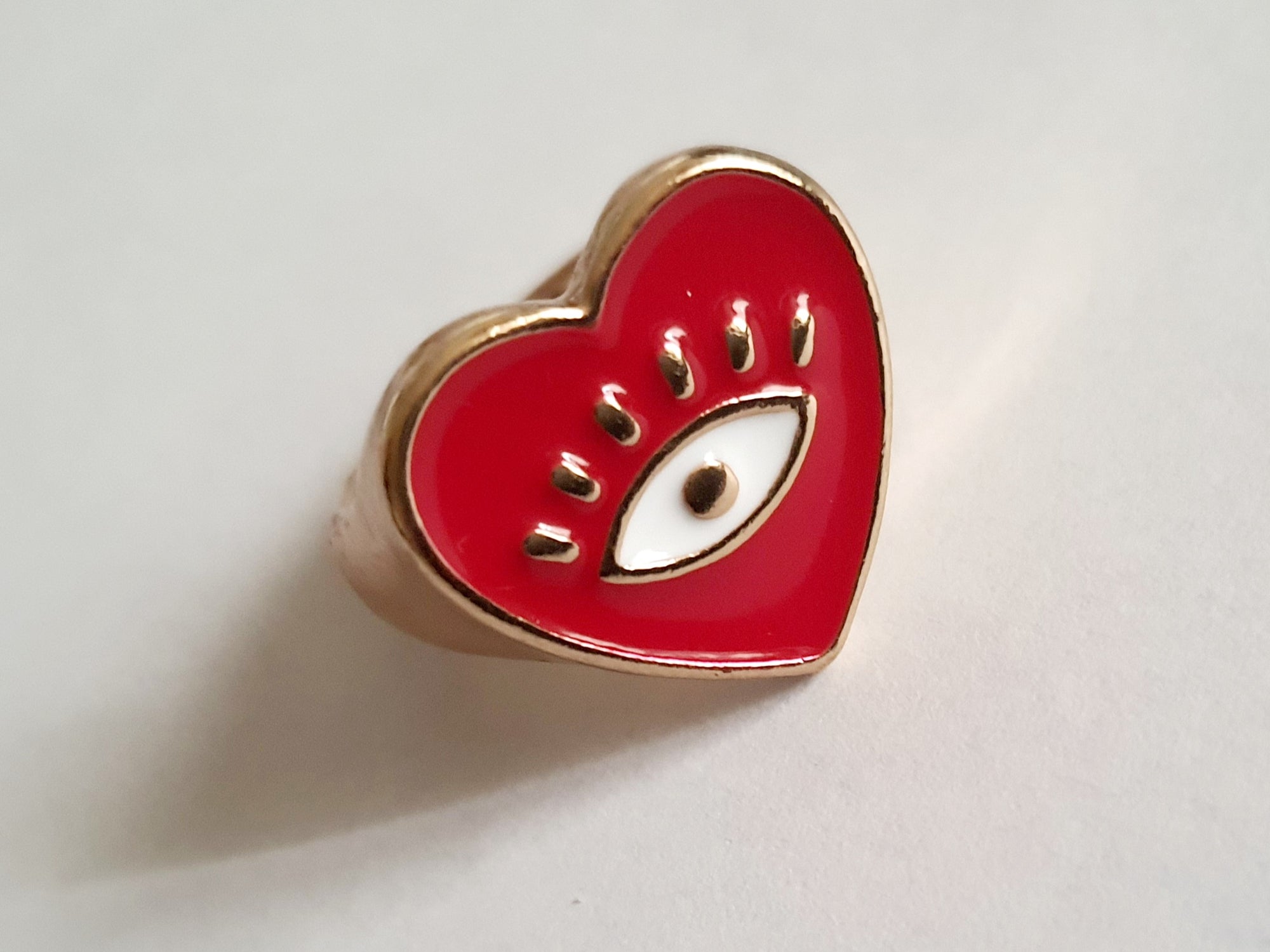 Złoty sygnet ze stali nierdzewnej w kształcie czerwonego serca z emaliowanym okiem. Styl zabawny, pop-artowy, symboliczny. Rozmiar 17 mm. Rouge Bizu.

