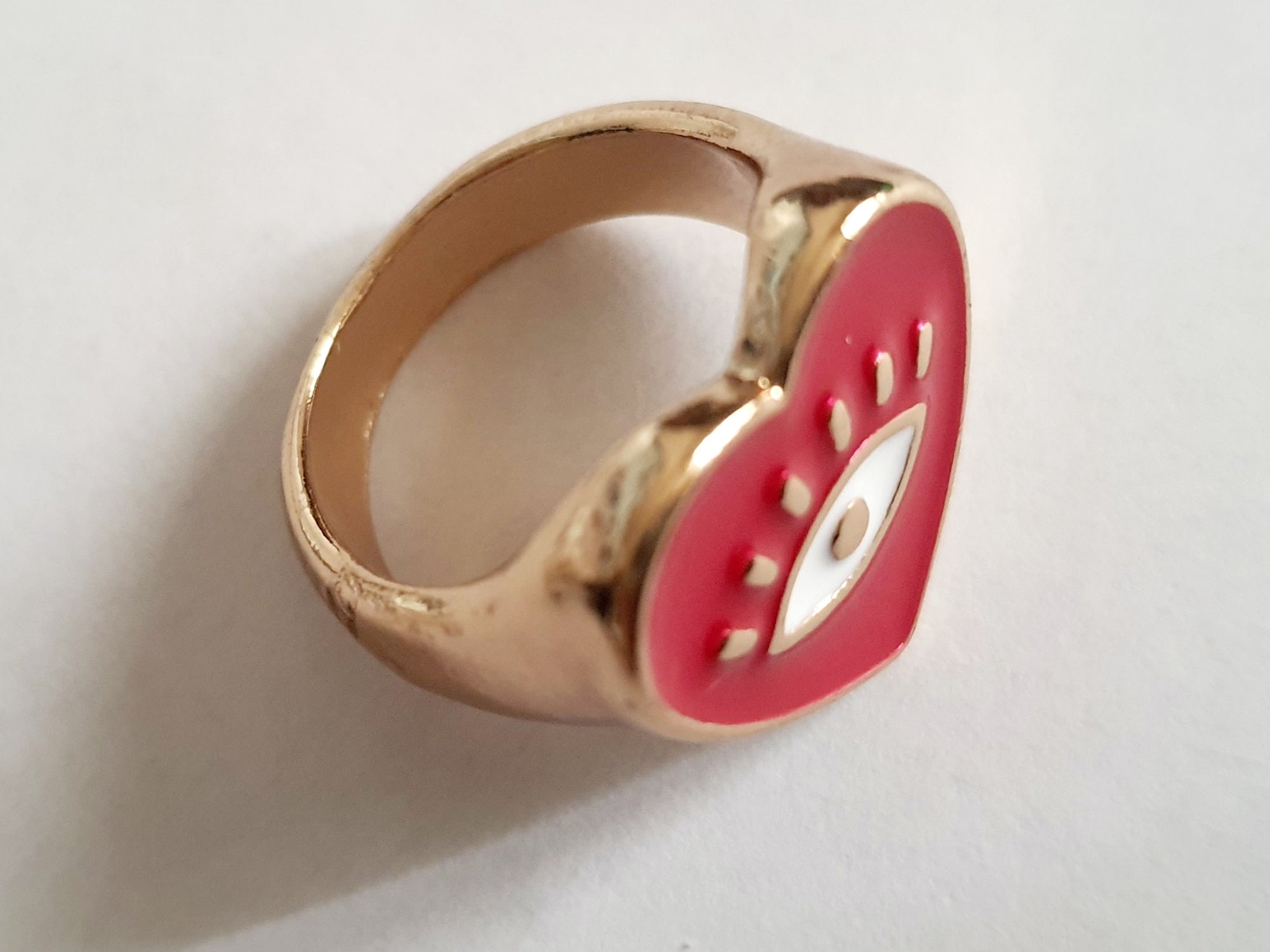 Złoty sygnet ze stali nierdzewnej w kształcie czerwonego serca z emaliowanym okiem. Styl zabawny, pop-artowy, symboliczny. Rozmiar 17 mm. Rouge Bizu.

