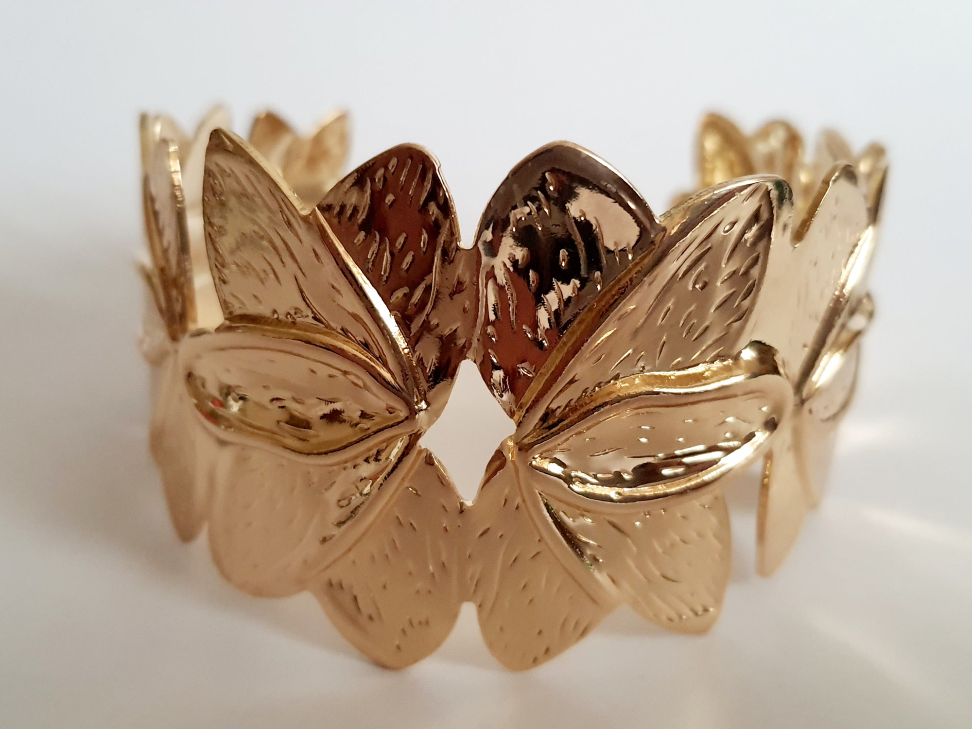Złota bransoletka ze stali nierdzewnej w formie splecionych liści, inspirowana naturą, elegancka i kobieca, średnica 6 cm. Styl glamour z nutą boho. Rouge Bizu.