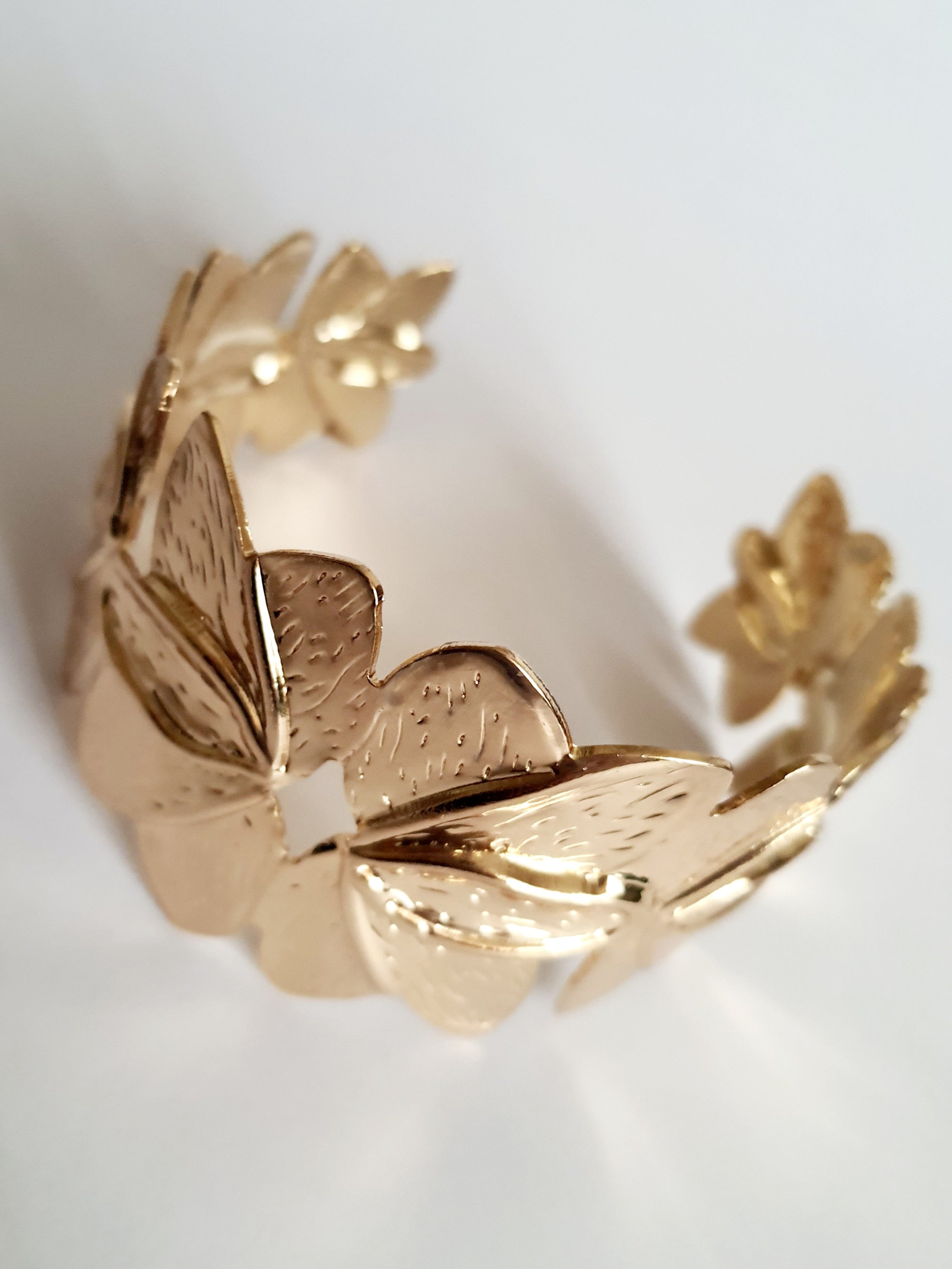 Złota bransoletka ze stali nierdzewnej w formie splecionych liści, inspirowana naturą, elegancka i kobieca, średnica 6 cm. Styl glamour z nutą boho. Rouge Bizu.