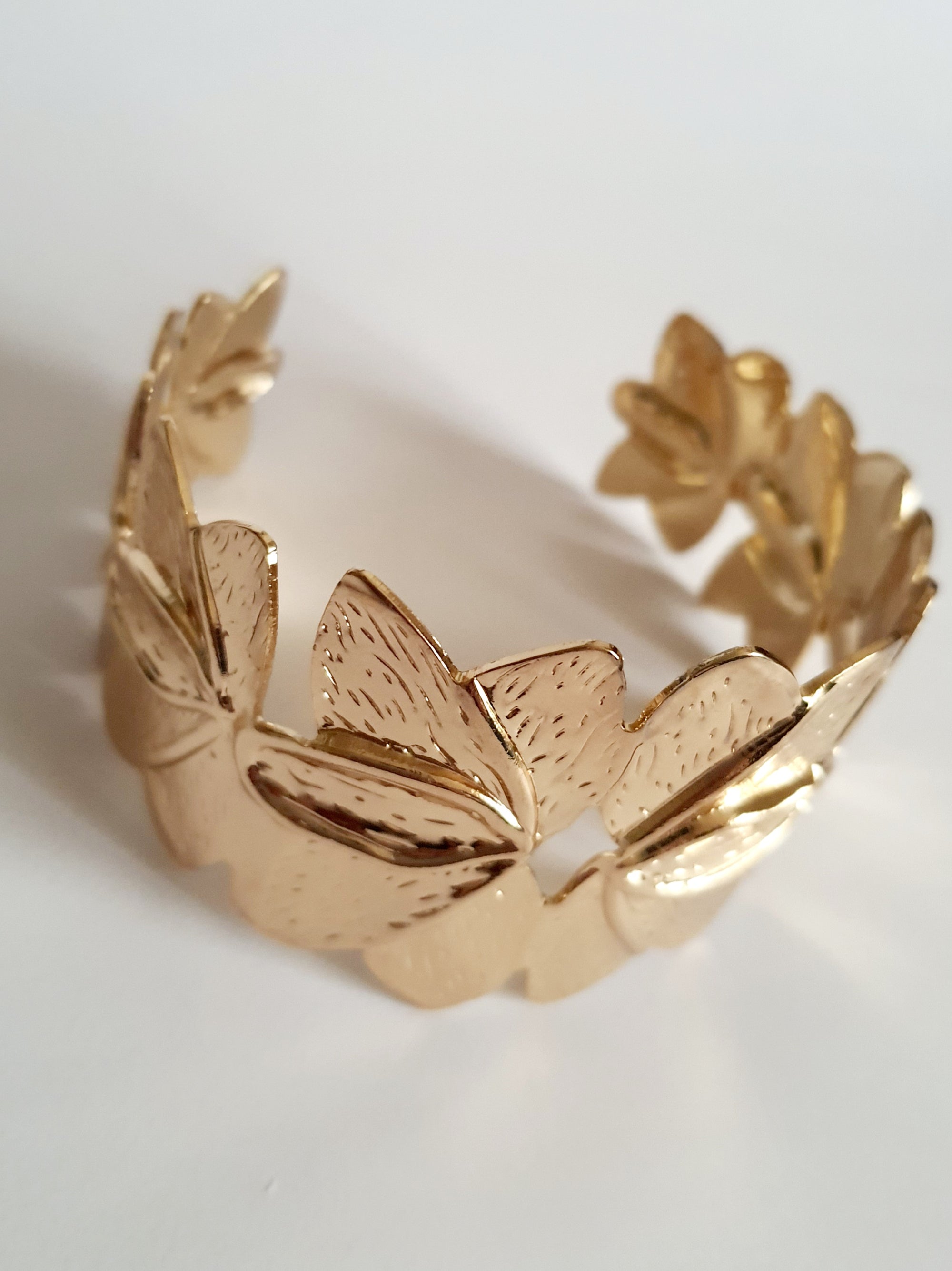 Złota bransoletka ze stali nierdzewnej w formie splecionych liści, inspirowana naturą, elegancka i kobieca, średnica 6 cm. Styl glamour z nutą boho. Rouge Bizu.