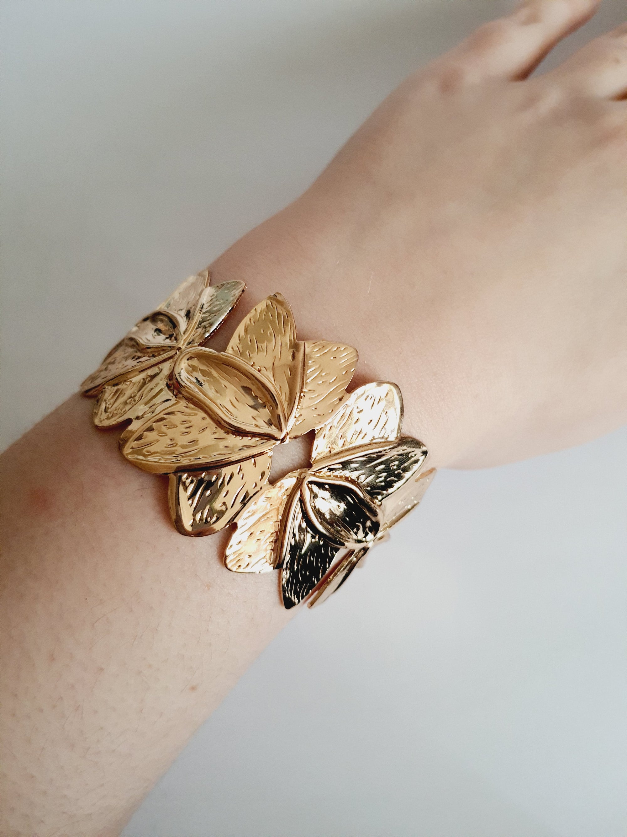 Złota bransoletka ze stali nierdzewnej w formie splecionych liści, inspirowana naturą, elegancka i kobieca, średnica 6 cm. Styl glamour z nutą boho. Rouge Bizu.