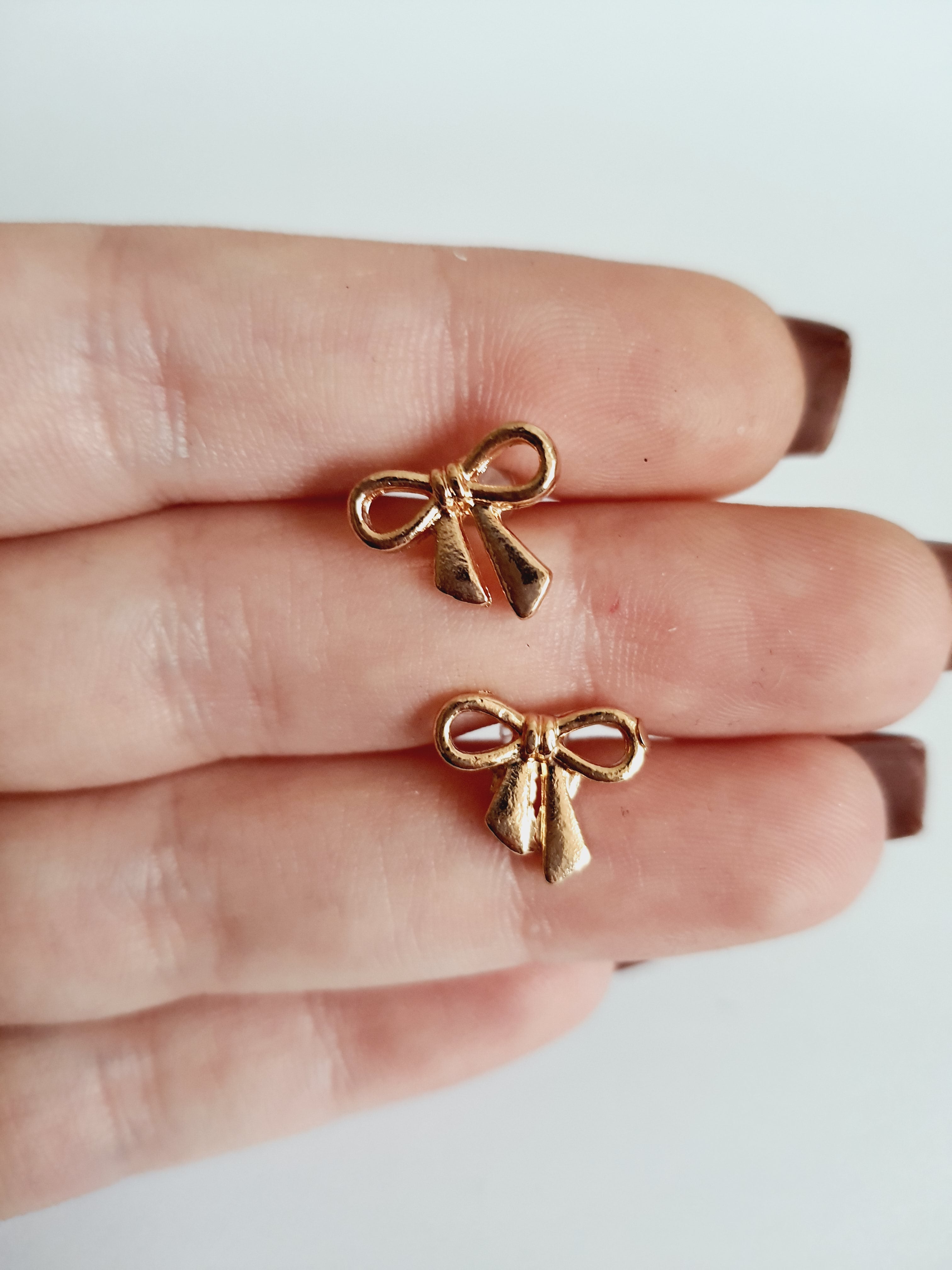 Złote kolczyki kokardki wkrętki, stal nierdzewna, długość 1,5 cm, subtelny romantyczny styl. Rouge Bizu.