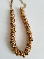 Złota bransoletka ze stali nierdzewnej, masywna forma ze splecionymi elementami, długość regulowana 18–24 cm, elegancki styl glamour. Rouge Bizu.
