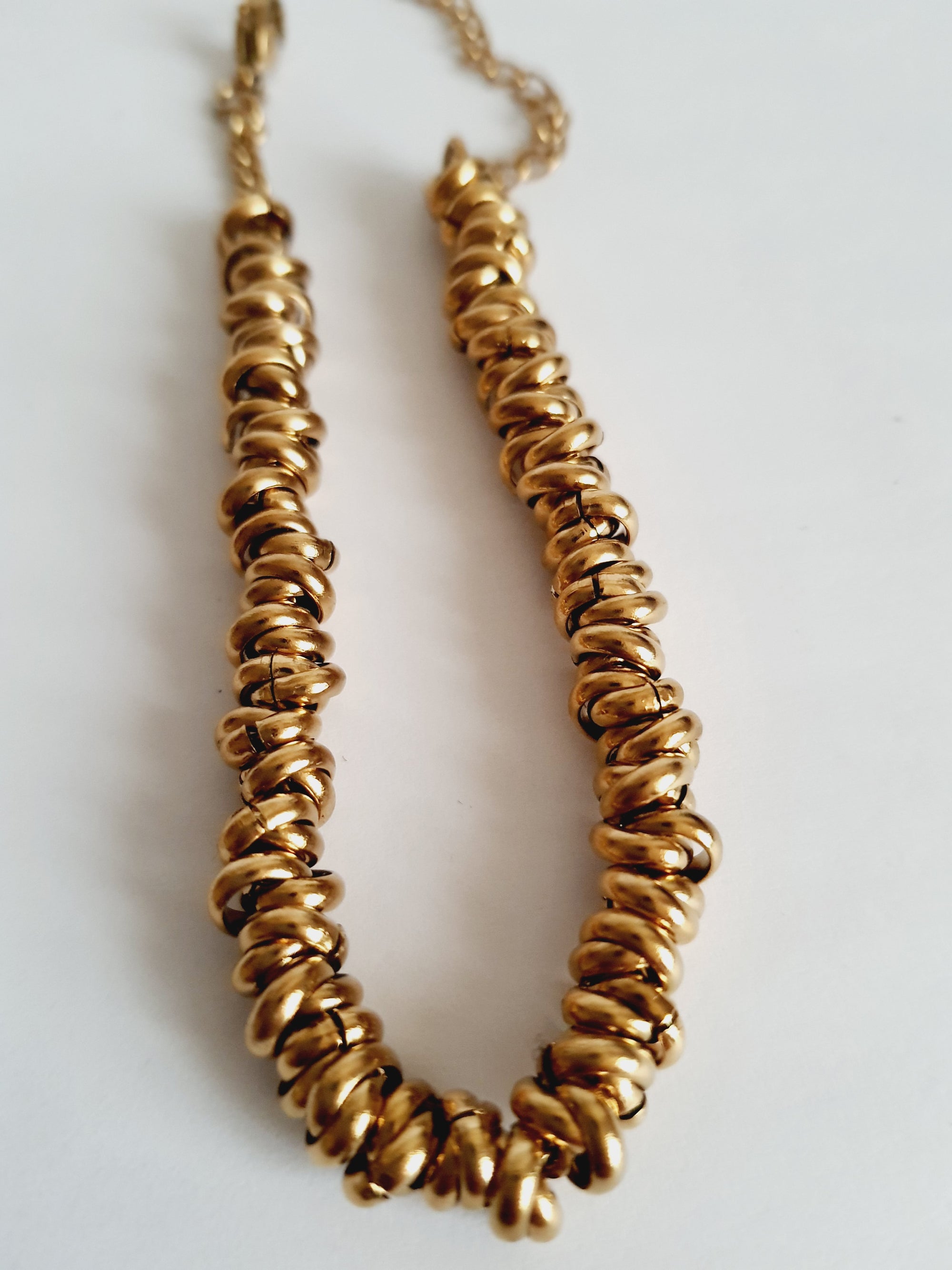 Złota bransoletka ze stali nierdzewnej, masywna forma ze splecionymi elementami, długość regulowana 18–24 cm, elegancki styl glamour. Rouge Bizu.
