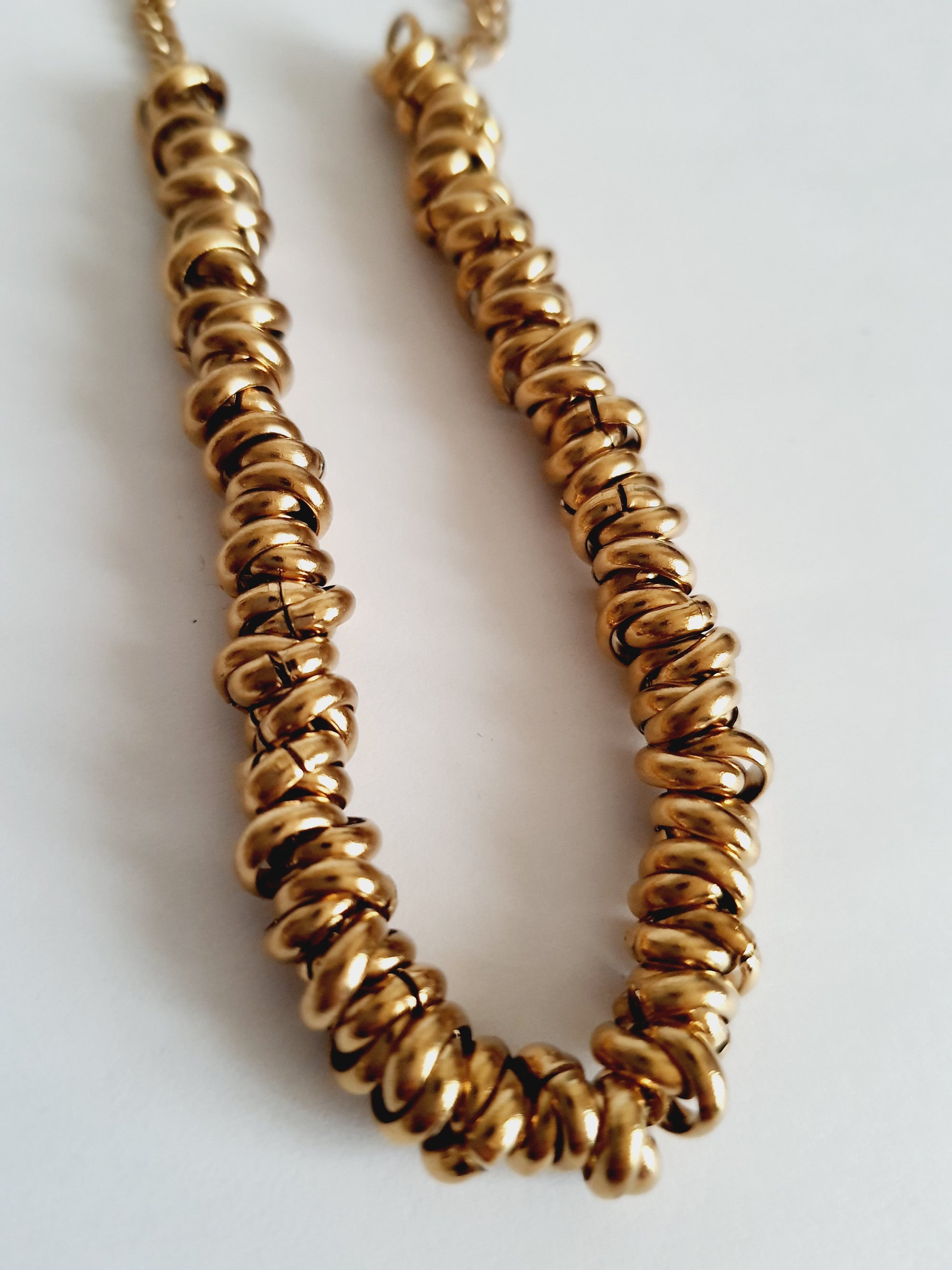 Złota bransoletka ze stali nierdzewnej, masywna forma ze splecionymi elementami, długość regulowana 18–24 cm, elegancki styl glamour. Rouge Bizu.