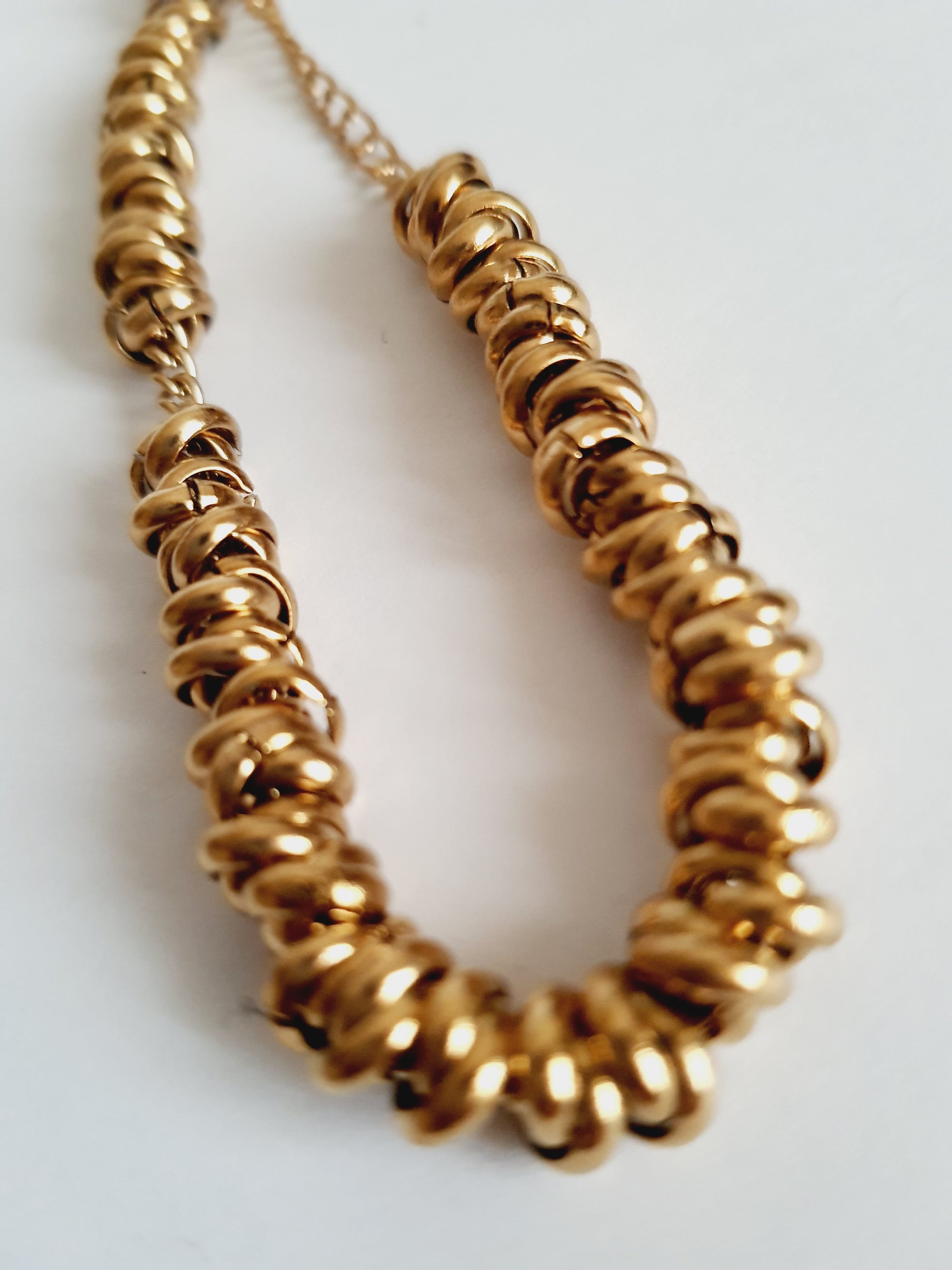 Złota bransoletka ze stali nierdzewnej, masywna forma ze splecionymi elementami, długość regulowana 18–24 cm, elegancki styl glamour. Rouge Bizu.