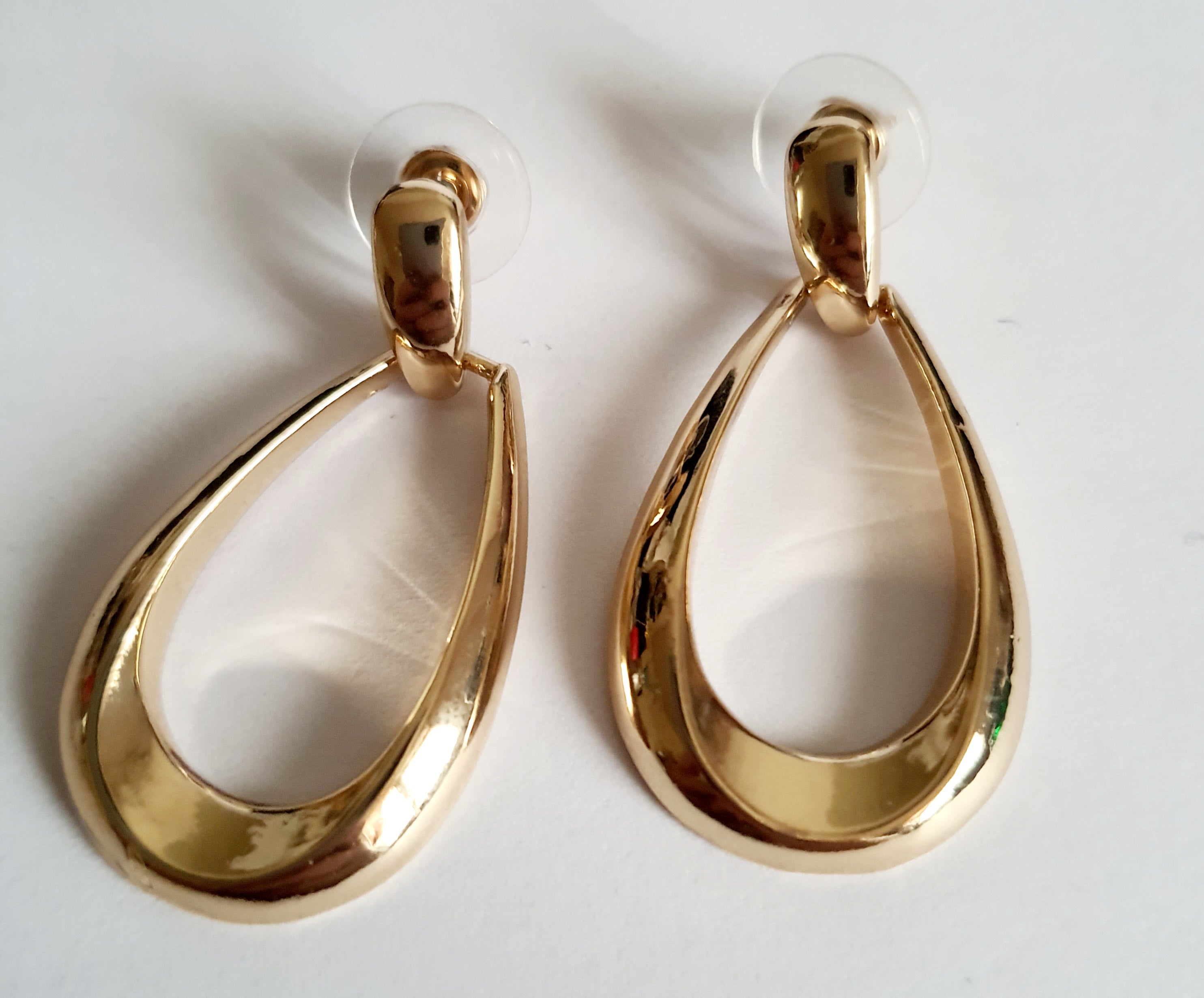 Złote kolczyki ze stali nierdzewnej w kształcie minimalistycznych kropli, eleganckie i ponadczasowe, długość 4 cm. Rouge Bizu.