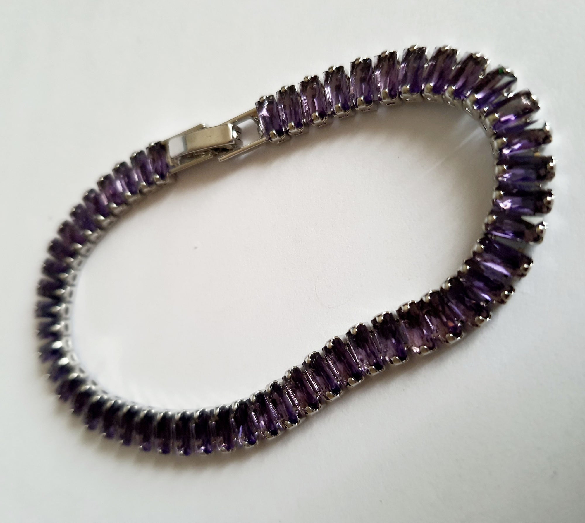 Srebrna bransoletka ze stali nierdzewnej zdobiona fioletowymi kamieniami syntetycznymi, długość 18 cm, elegancki i wieczorowy styl glamour. Rouge Bizu.