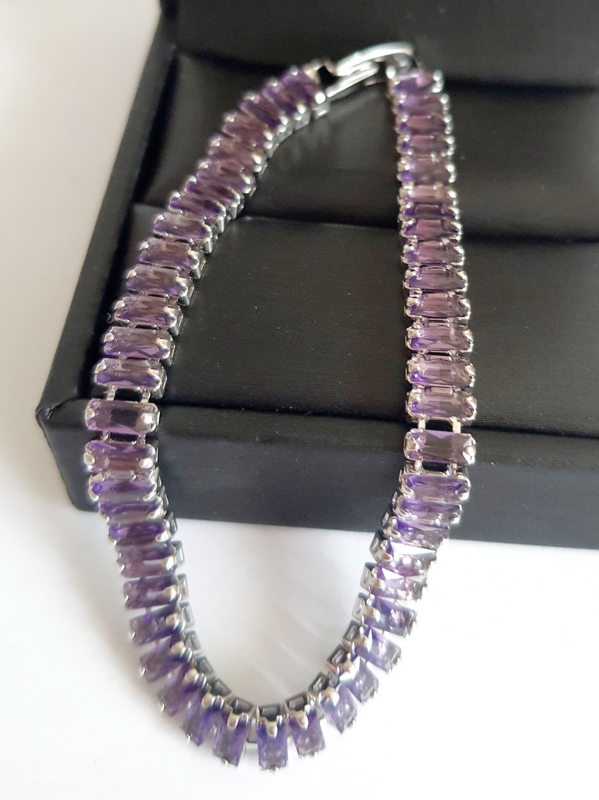 Srebrna bransoletka ze stali nierdzewnej zdobiona fioletowymi kamieniami syntetycznymi, długość 18 cm, elegancki i wieczorowy styl glamour. Rouge Bizu.