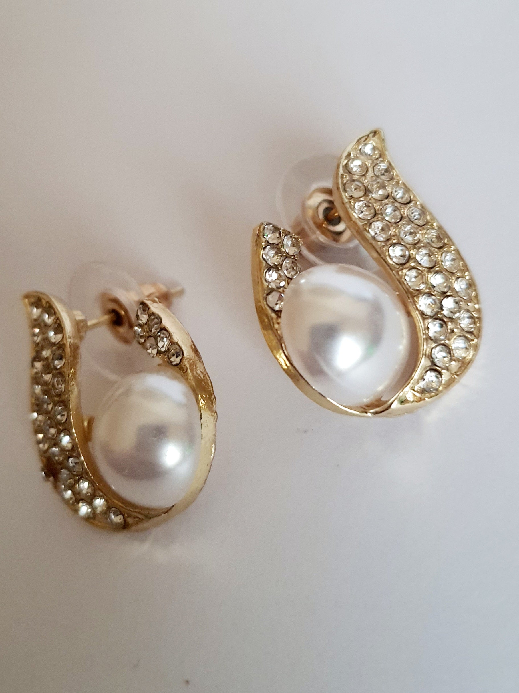 Kolczyki złote ze stali nierdzewnej o długości 2 cm, z białą perłą i oprawą wysadzaną cyrkoniami, elegancki kształt z falującą linią, Rouge Bizu.