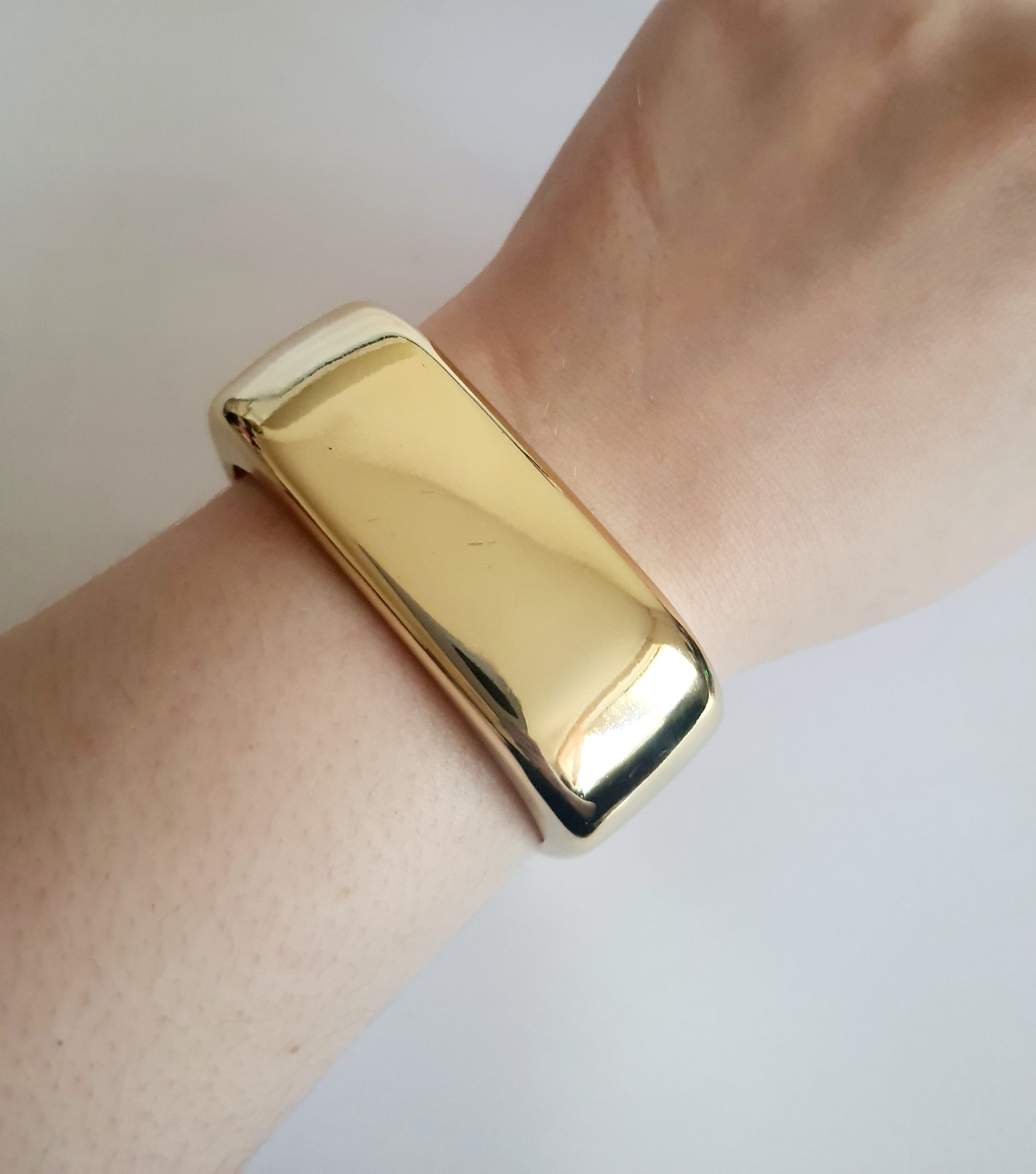 Złota sztywna bransoletka ze stali nierdzewnej, geometryczna forma, średnica 6 cm, gładka powierzchnia, minimalistyczny i elegancki design, Rouge Bizu.