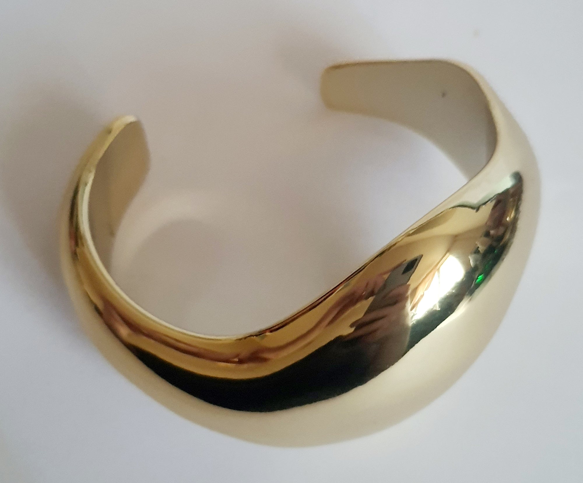 Złota sztywna bransoletka ze stali nierdzewnej, rzeźbiarska i falująca forma, średnica 6 cm, artystyczny i nowoczesny design, Rouge Bizu.