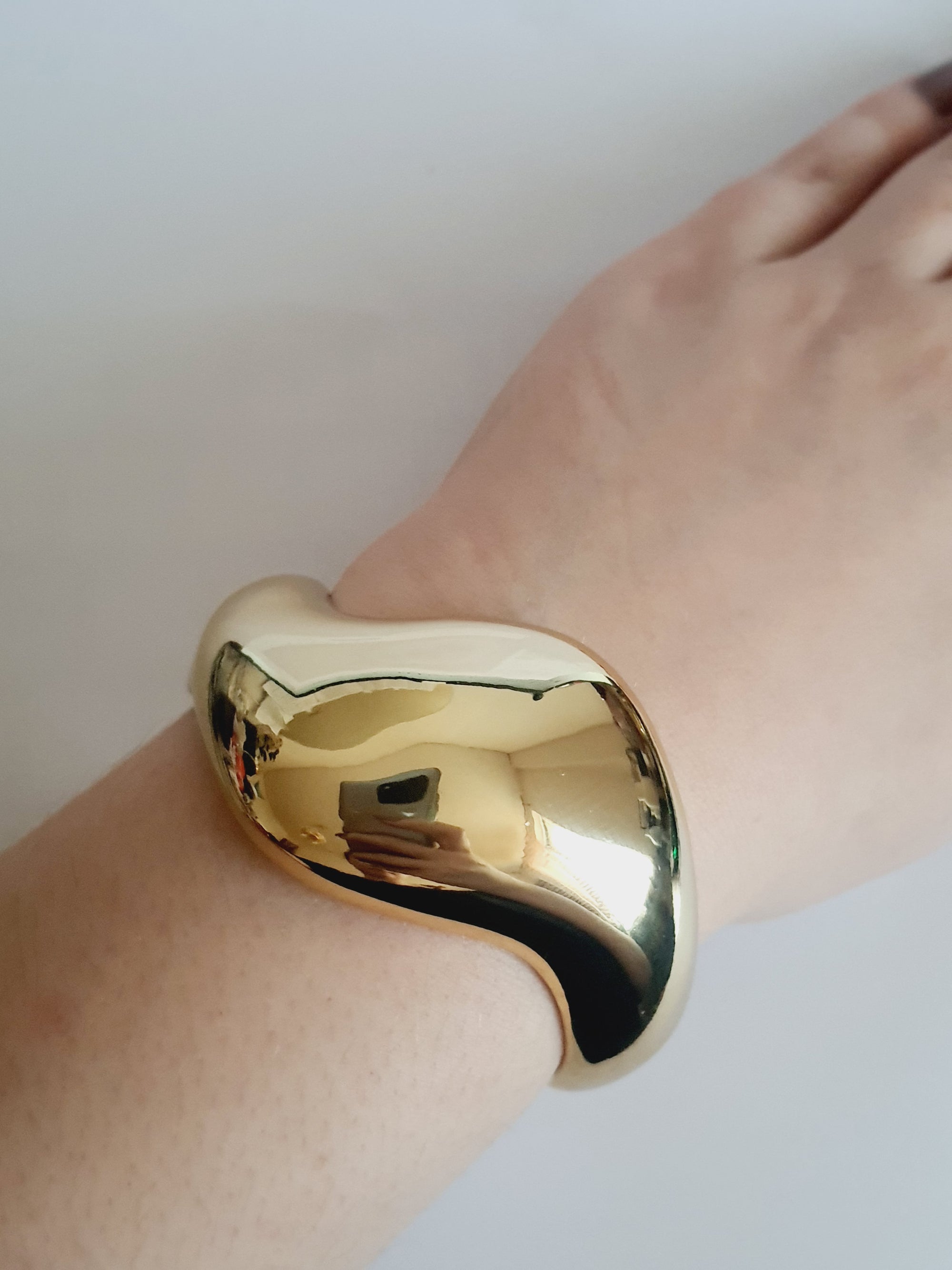 Złota sztywna bransoletka ze stali nierdzewnej, rzeźbiarska i falująca forma, średnica 6 cm, artystyczny i nowoczesny design, Rouge Bizu.