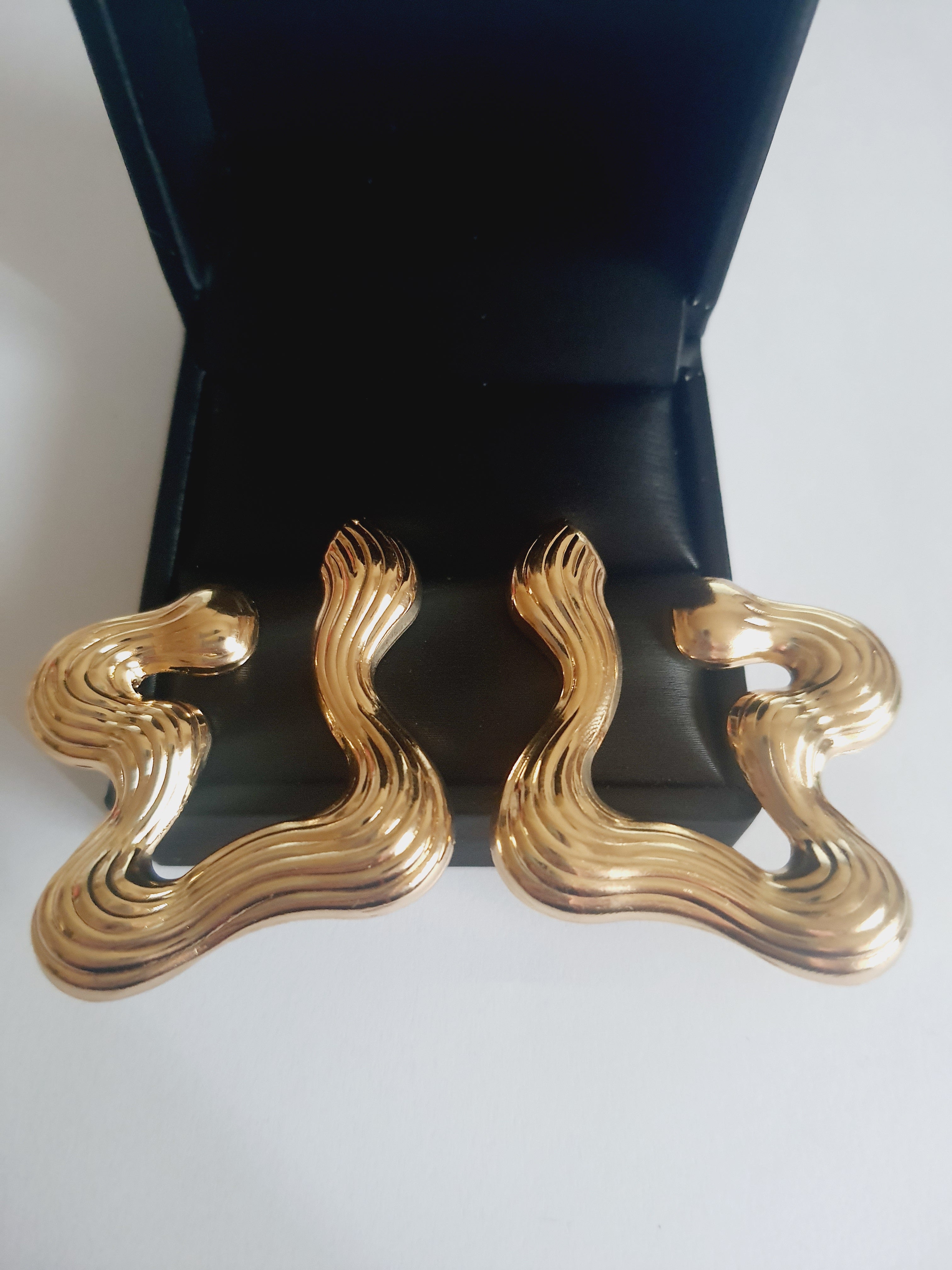 Złote kolczyki falujące o artystycznej, nieregularnej formie, eleganckie i nowoczesne. Stal nierdzewna, długość 5 cm. Rouge Bizu.