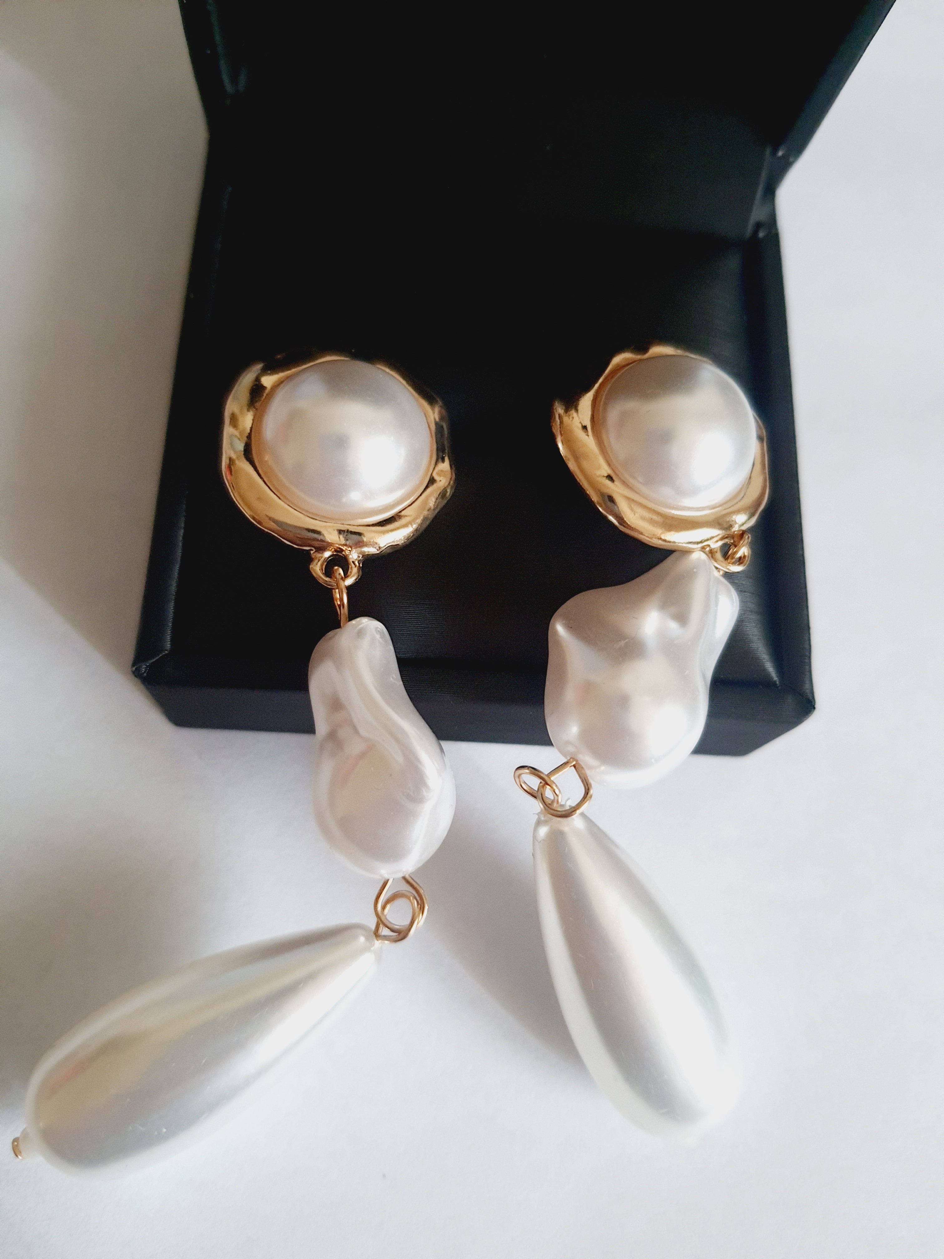 Długie złote kolczyki ze stali nierdzewnej z potrójnymi perłami: okrągłą, nieregularną i kroplą. Styl glamour, klasyczna elegancja. Długość 9 cm. Rouge Bizu.