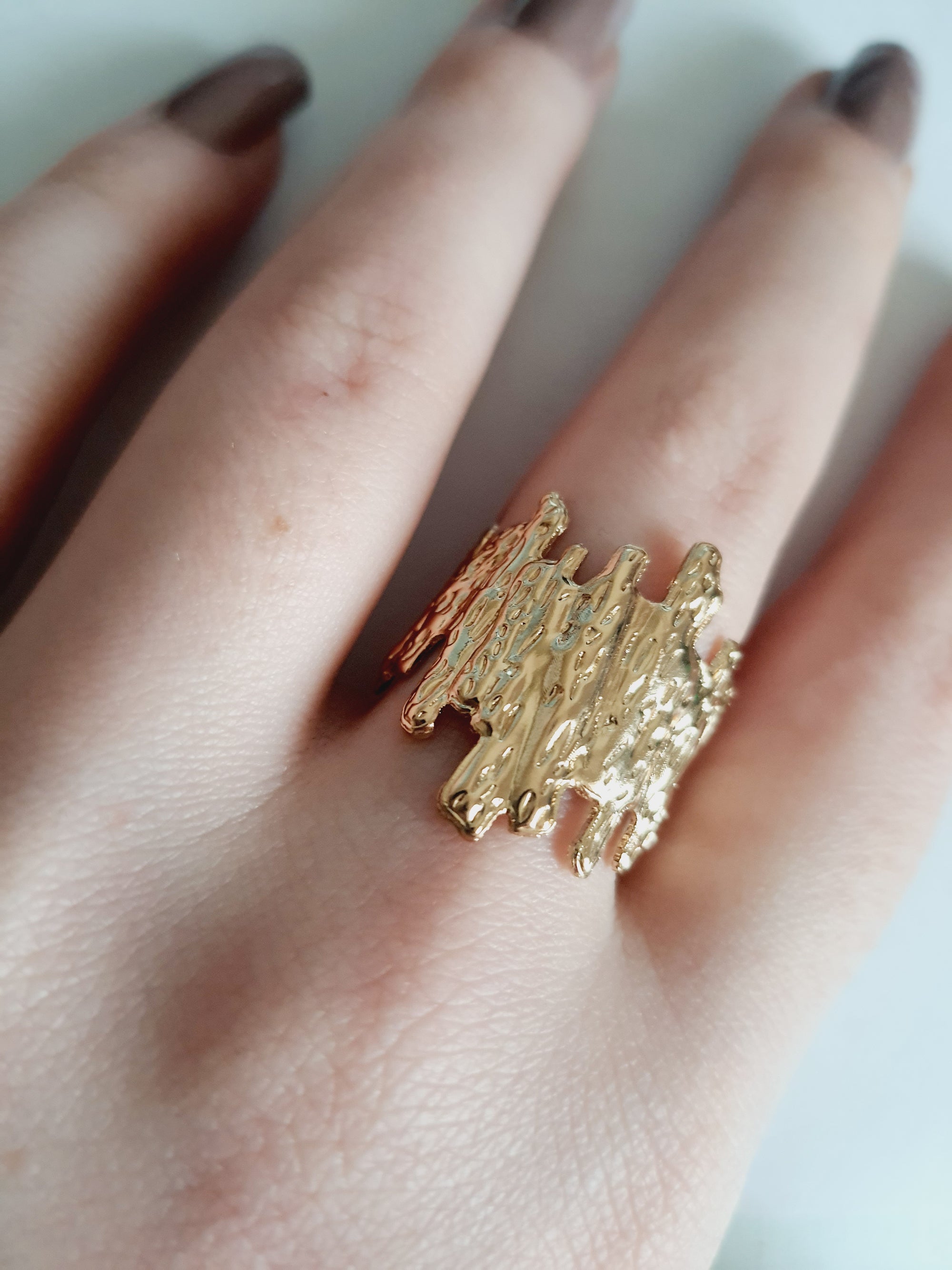 Złoty pierścionek ze stali nierdzewnej o organicznej fakturze, przypominającej skałę lub strukturę kory. Styl artystyczny i nowoczesny. Rozmiar 19 mm. Rouge Bizu.