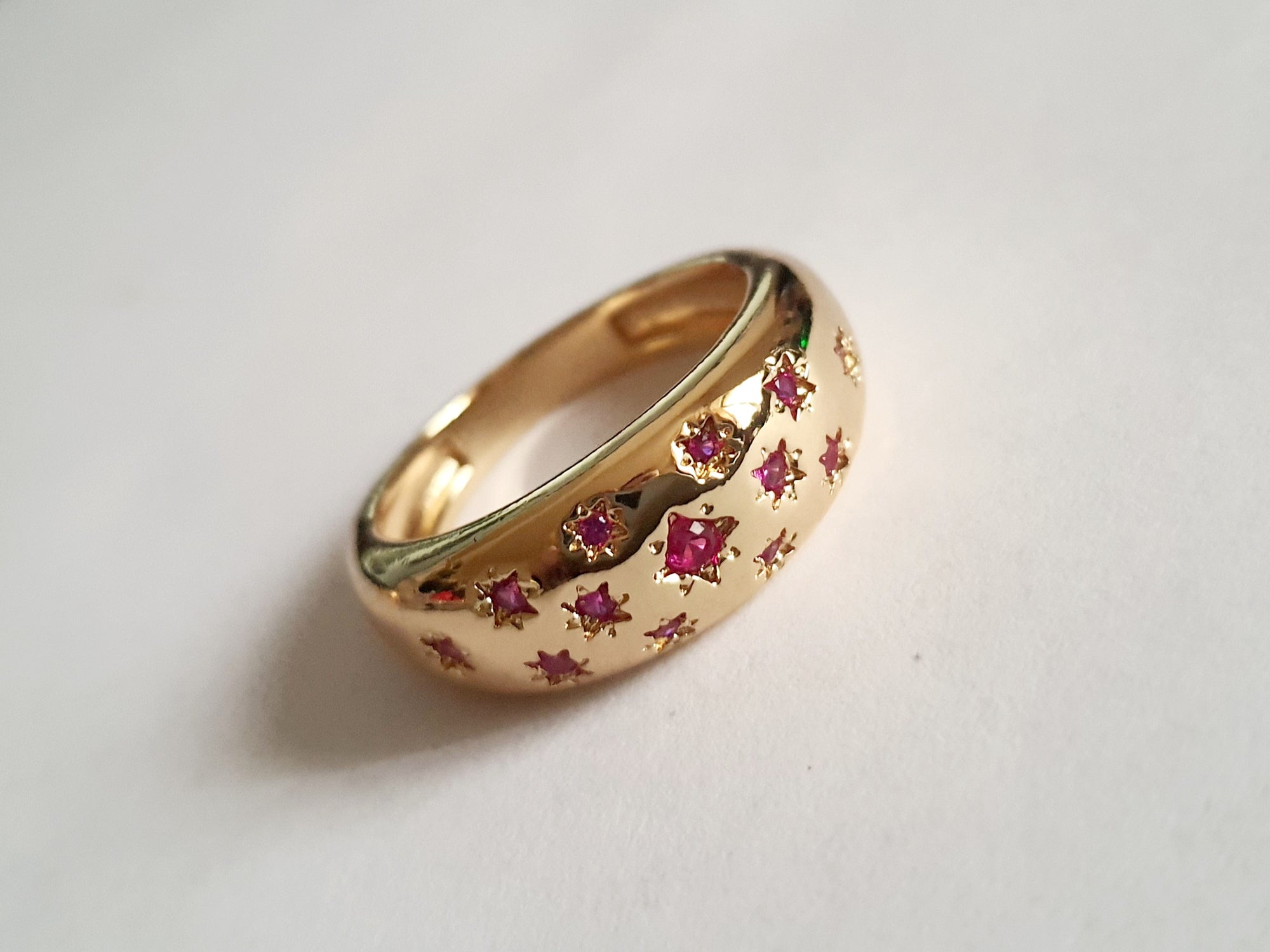 Złoty pierścionek ze stali nierdzewnej, ozdobiony czerwonymi kryształami w kształcie gwiazd. Elegancki, oryginalny, w stylu glamour. Rozmiar 20 mm. Rouge Bizu.