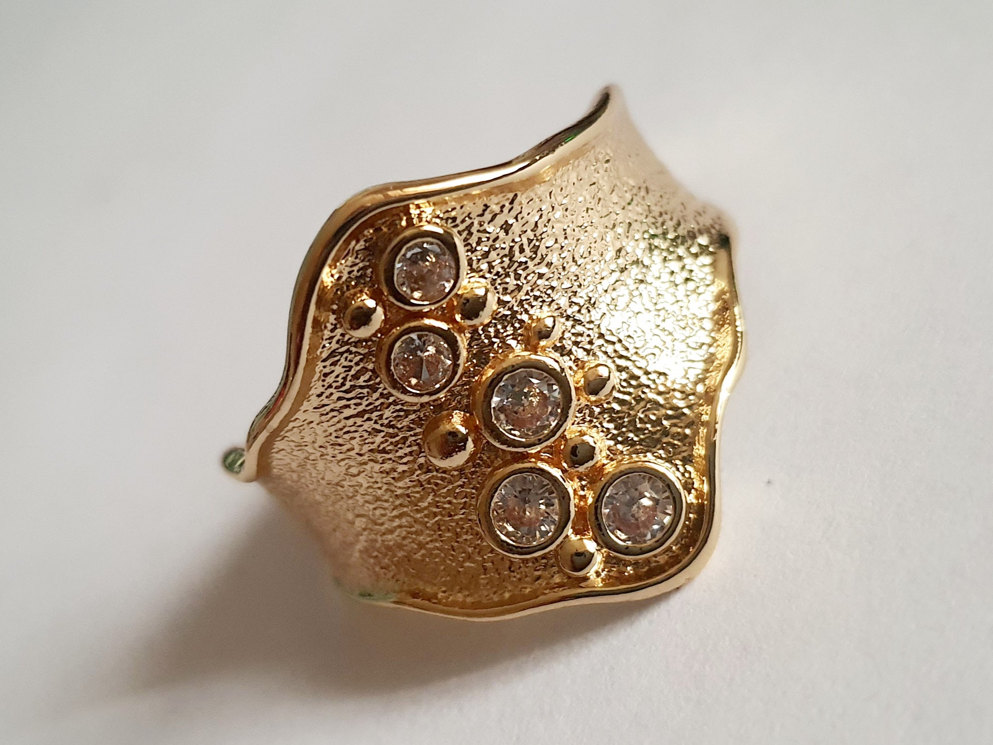 Szeroki złoty pierścionek ze stali nierdzewnej o młotkowanej fakturze, ozdobiony rzędem przezroczystych cyrkonii. Styl glamour, elegancja. Rozmiar 21 mm. Rouge Bizu.