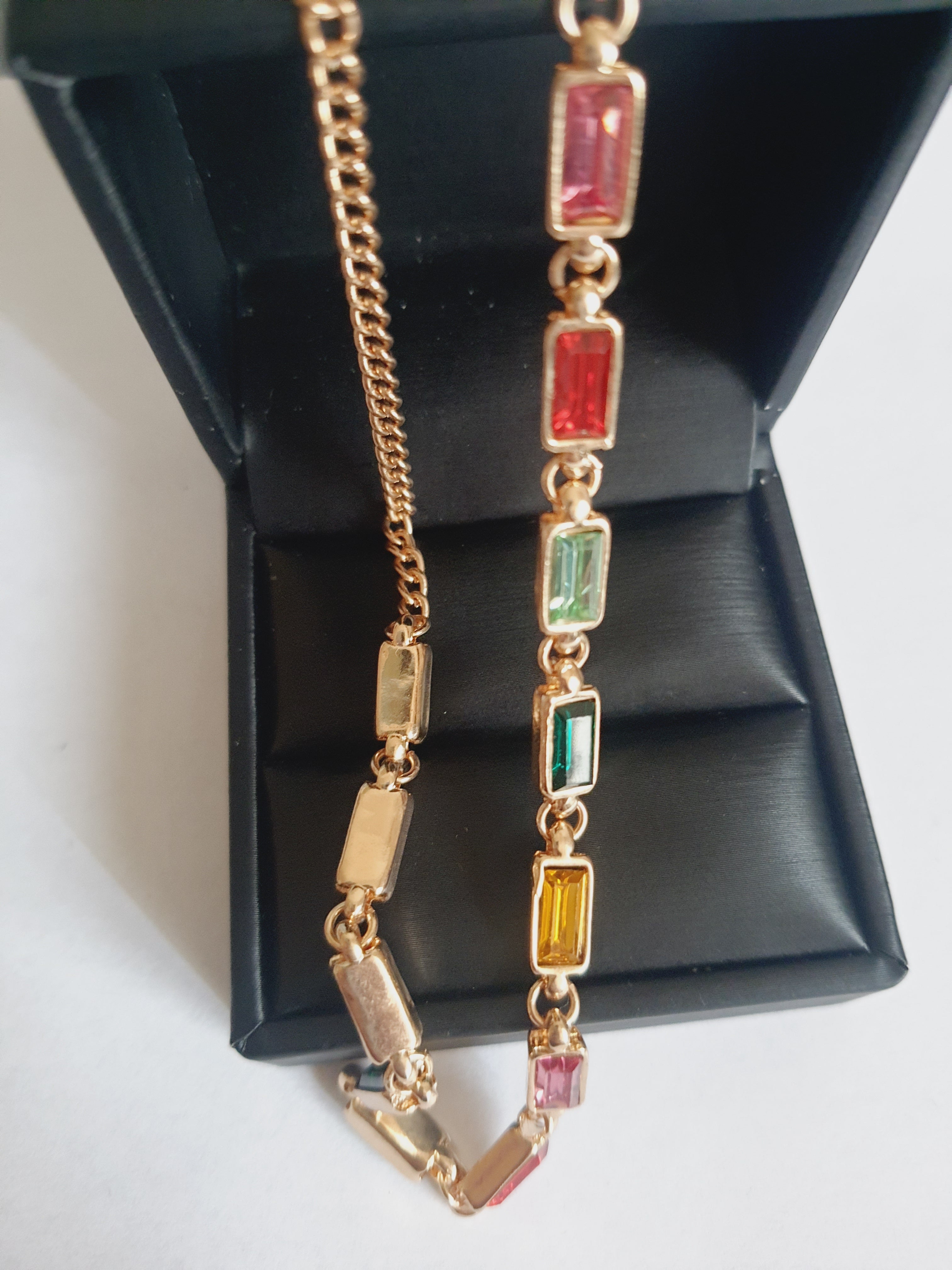 Złoty naszyjnik ze stali nierdzewnej z prostokątnymi, wielobarwnymi kryształami w odcieniach zieleni, czerwieni, różu, złota i turkusu. Długość 41–47 cm. Rouge Bizu.