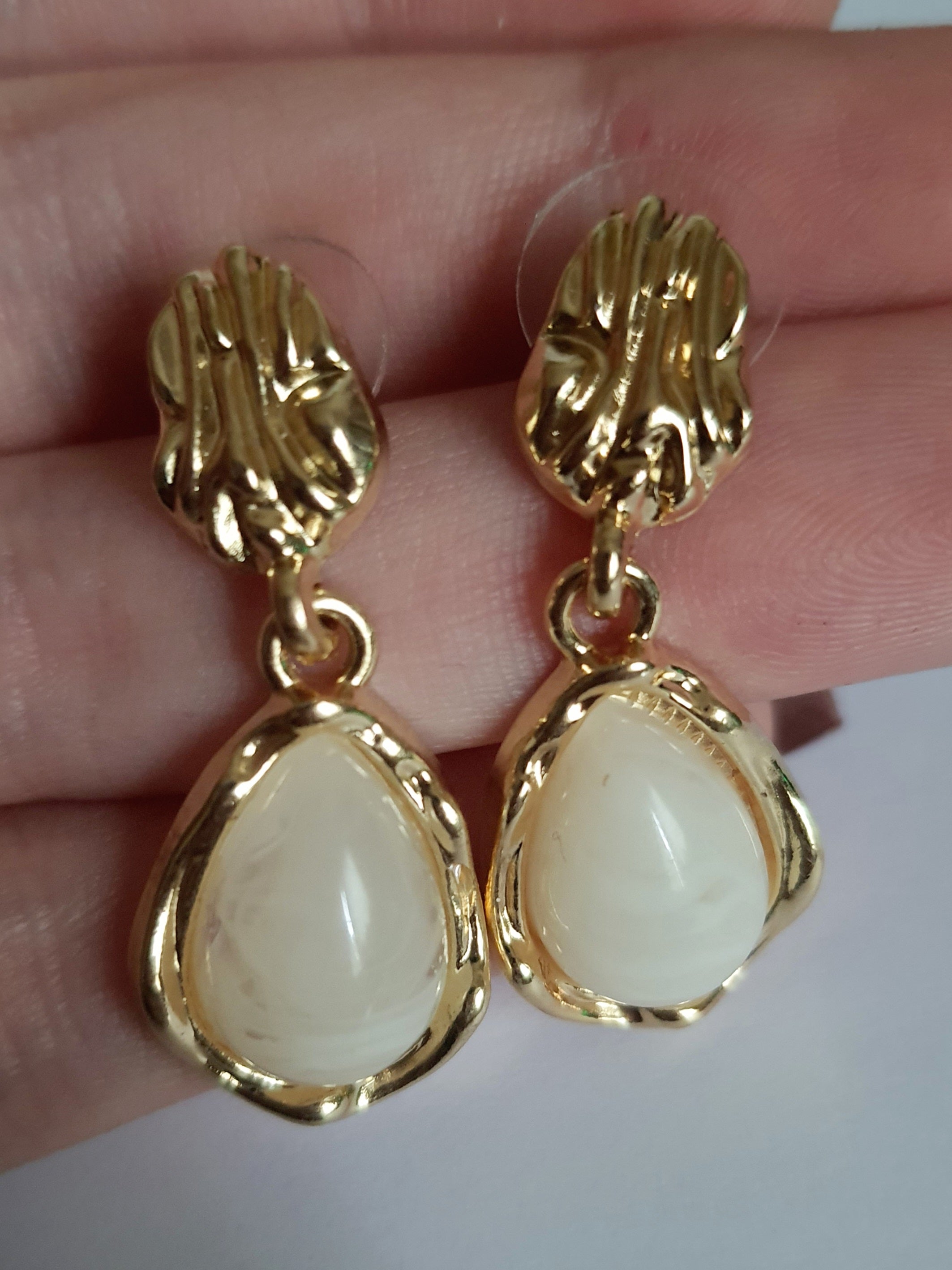 „Złote kolczyki ze stali nierdzewnej o długości 3 cm, zdobione perłowym kaboszonem w kształcie kropli, eleganckie i klasyczne – Rouge Bizu.”