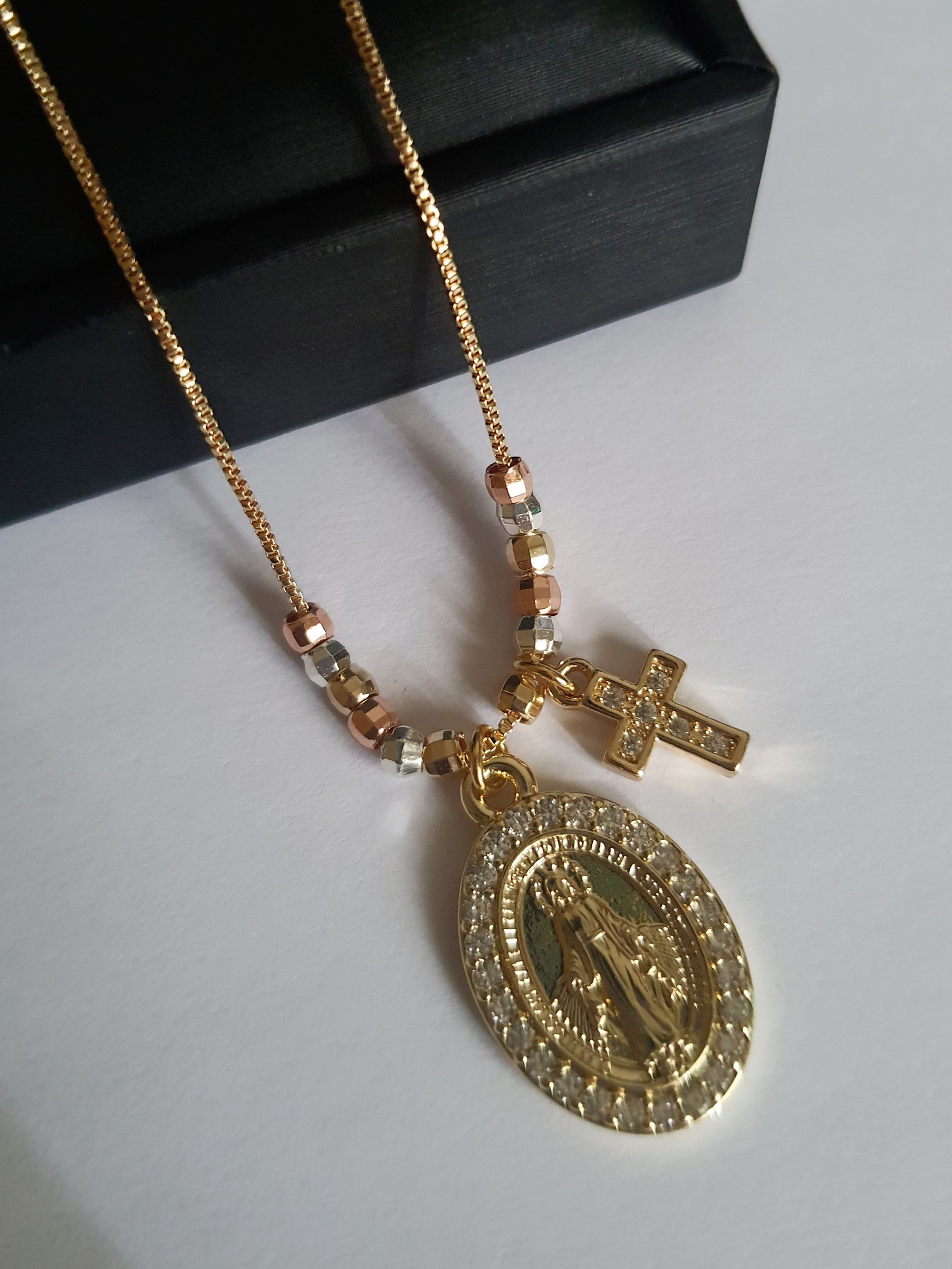 „Złoty naszyjnik ze stali nierdzewnej o długości do 48 cm, z medalikiem Matki Boskiej zdobionym cyrkoniami i krzyżykiem z kryształami, elegancki i symboliczny – Rouge Bizu.”