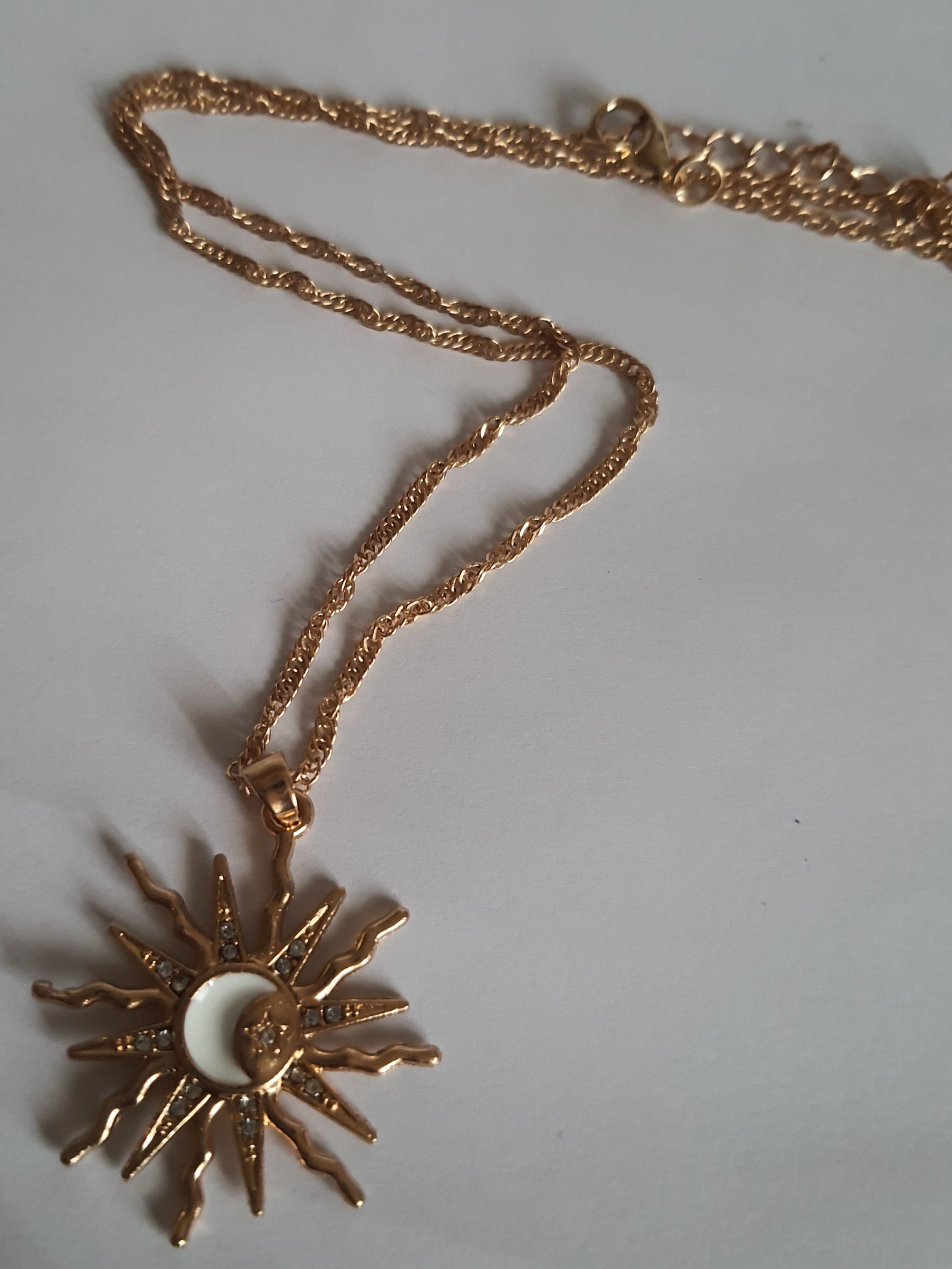 Naszyjnik ze stali nierdzewnej w kolorze złotym, z zawieszką w kształcie słońca i księżyca ozdobioną kryształkami, długość łańcuszka 42–47 cm, Rouge Bizu.