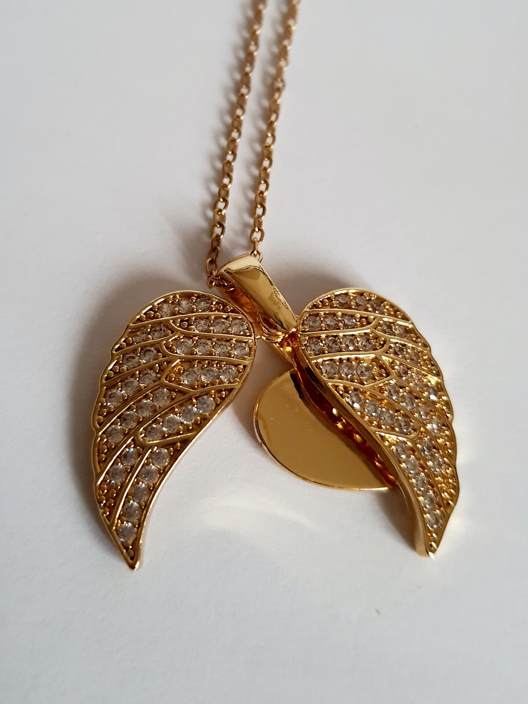 Naszyjnik ze stali nierdzewnej w kolorze złotym, z zawieszką serce i rozkładanymi skrzydłami ozdobionymi kryształkami, regulowana długość 40–45 cm, Rouge Bizu.