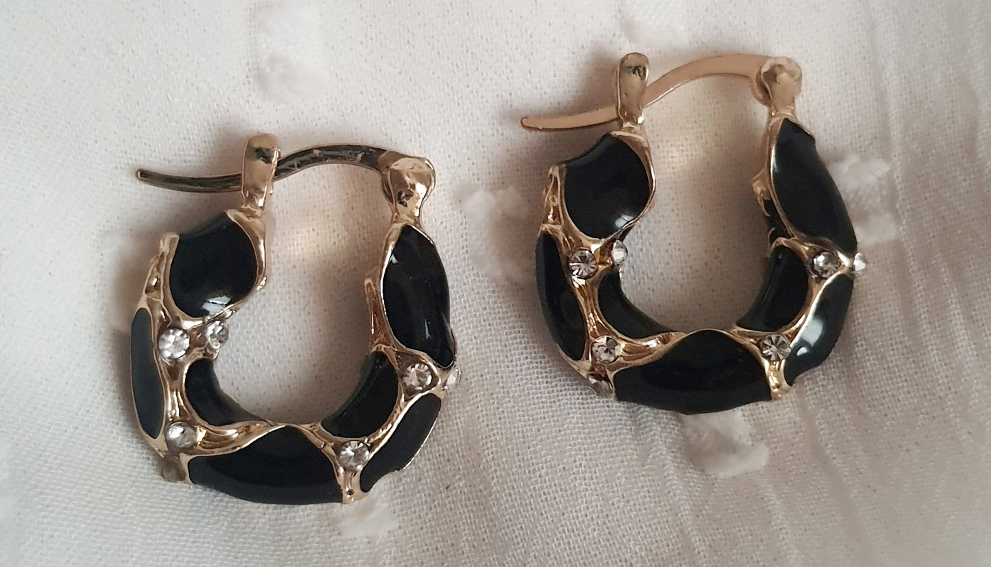 Kolczyki damskie ze stali nierdzewnej, średnica 2 cm, złote mini kółka z czarnymi zdobieniami i przezroczystymi kryształkami, elegancki i nowoczesny styl glamour, Rouge Bizu.
