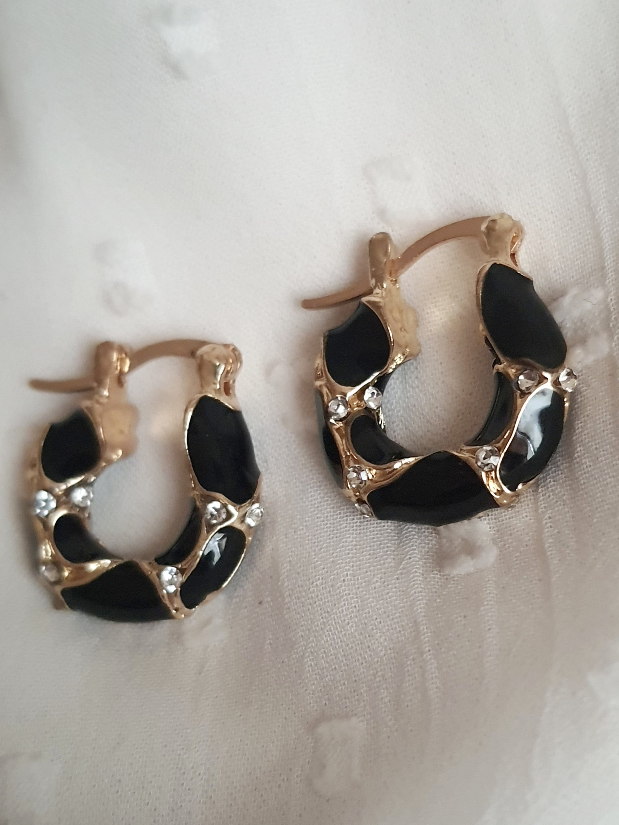 Kolczyki damskie ze stali nierdzewnej, średnica 2 cm, złote mini kółka z czarnymi zdobieniami i przezroczystymi kryształkami, elegancki i nowoczesny styl glamour, Rouge Bizu.