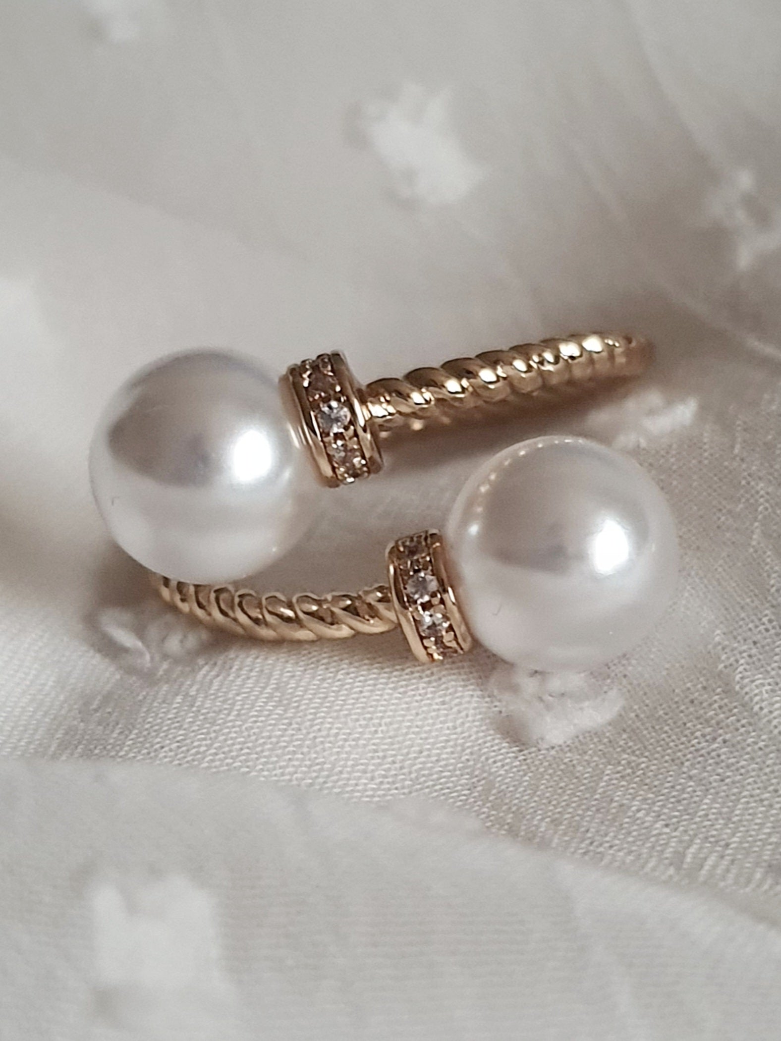 Pierścionek damski ze stali nierdzewnej, złoty, rozmiar 19 mm, zdobiony dwiema syntetycznymi perłami i drobnymi cyrkoniami, pleciona obrączka, elegancki styl glamour, Rouge Bizu.