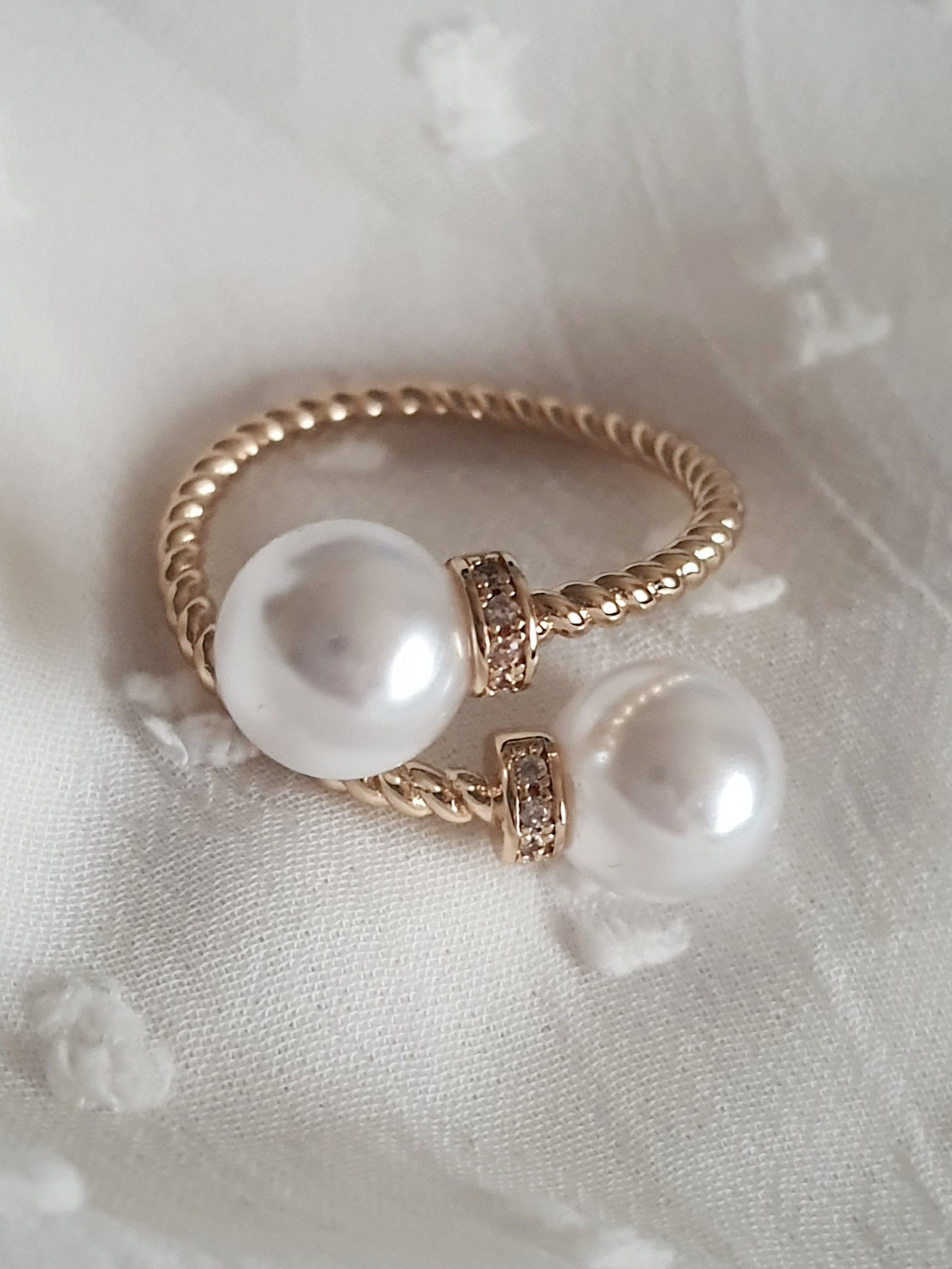 Pierścionek damski ze stali nierdzewnej, złoty, rozmiar 19 mm, zdobiony dwiema syntetycznymi perłami i drobnymi cyrkoniami, pleciona obrączka, elegancki styl glamour, Rouge Bizu.