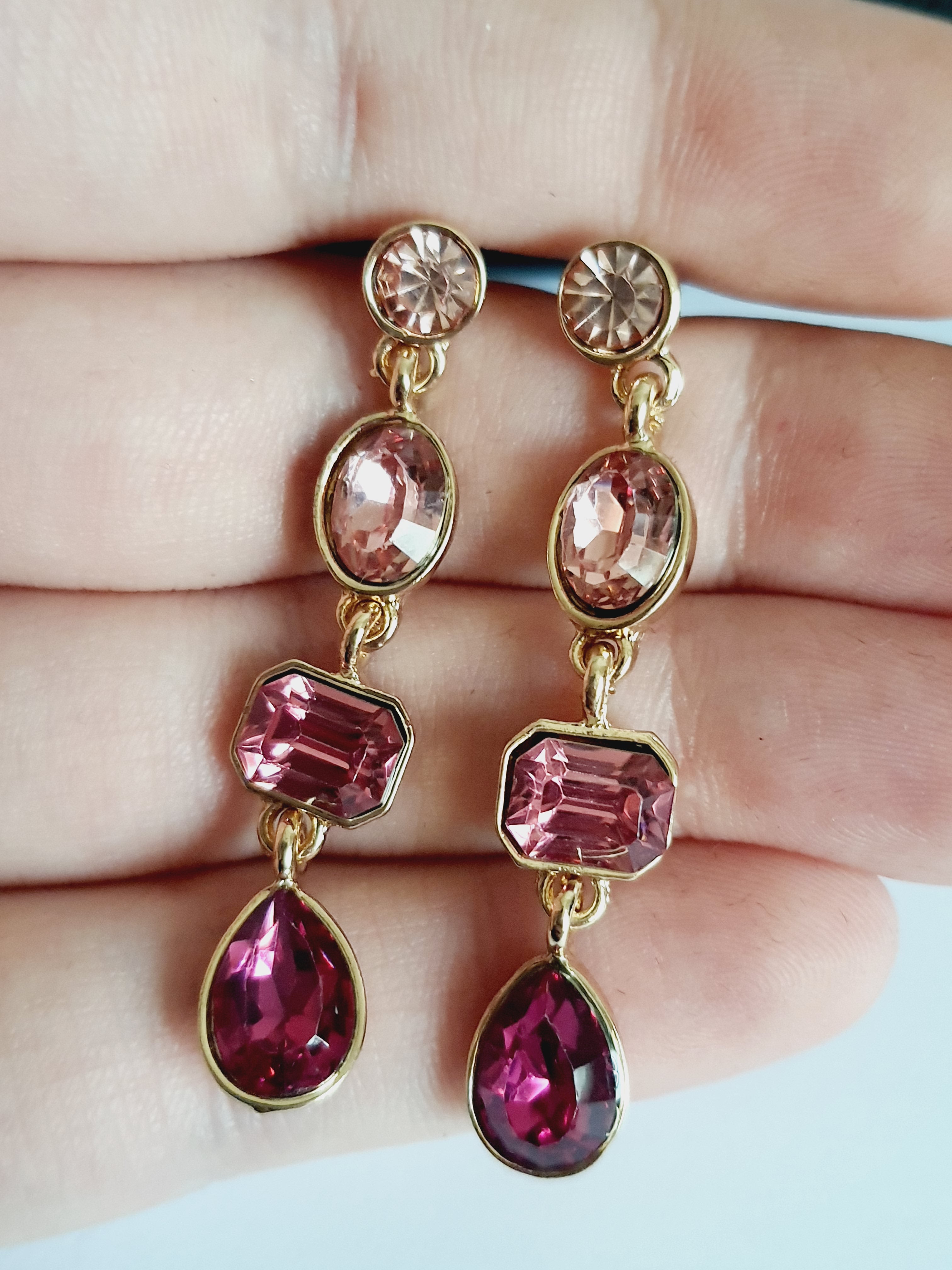 Długie kolczyki wiszące ze stali nierdzewnej w kolorze złota, z różowymi kryształami w kształcie owalu, prostokąta i kropli. Długość 4,5 cm. Styl glamour, elegancki. Rouge Bizu.