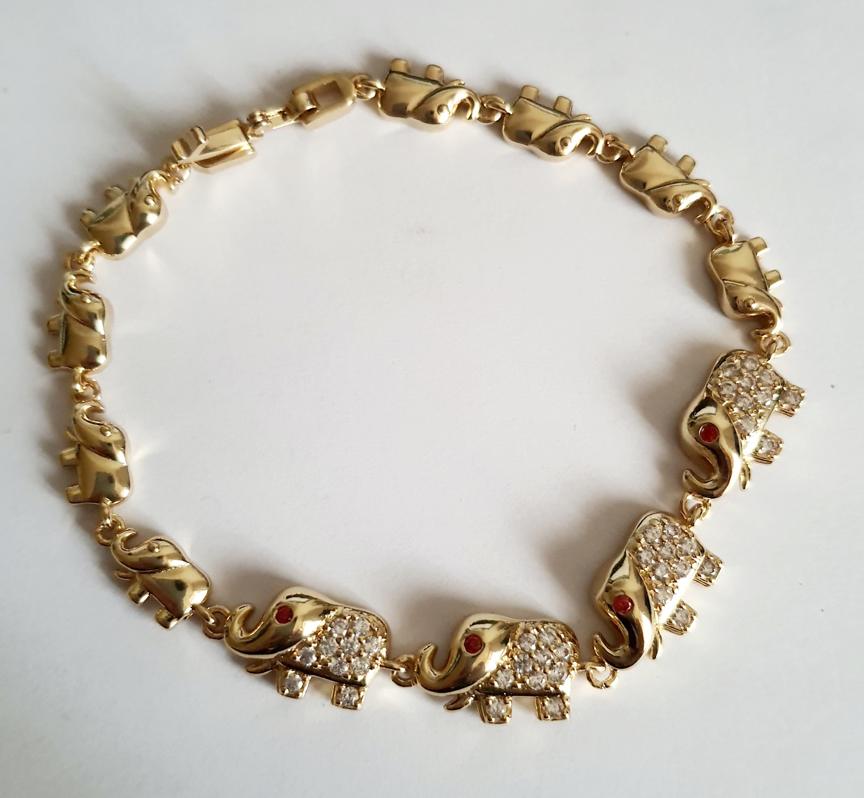 Bransoletka ze stali nierdzewnej w kolorze złota z motywem słoni, zdobiona cyrkoniami i czerwonymi oczkami. Symbol szczęścia, długość 20 cm. Rouge Bizu.