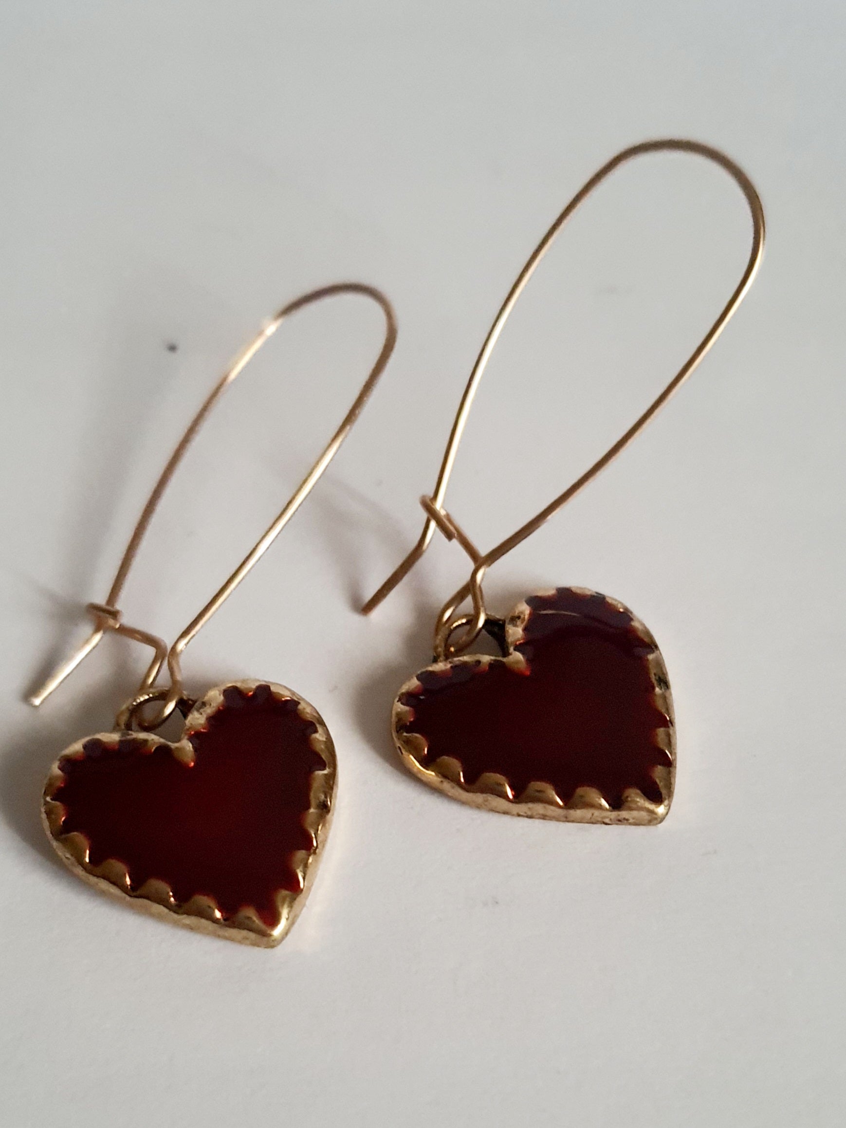 Kolczyki wiszące ze stali nierdzewnej w kolorze złota, z zawieszkami w kształcie czerwonych serc. Długość 5 cm. Styl romantyczny i elegancki. Rouge Bizu.