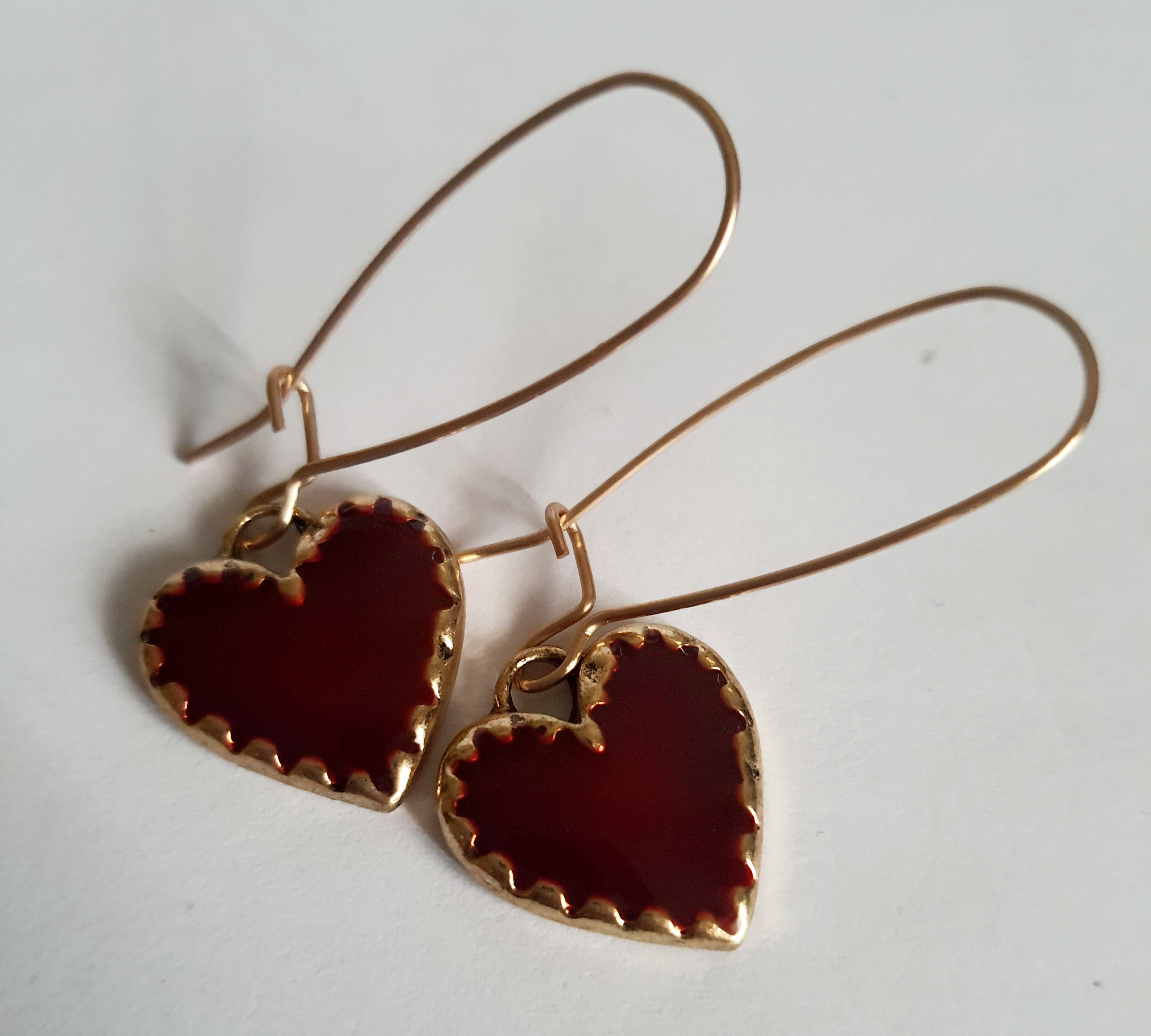 Kolczyki wiszące ze stali nierdzewnej w kolorze złota, z zawieszkami w kształcie czerwonych serc. Długość 5 cm. Styl romantyczny i elegancki. Rouge Bizu.