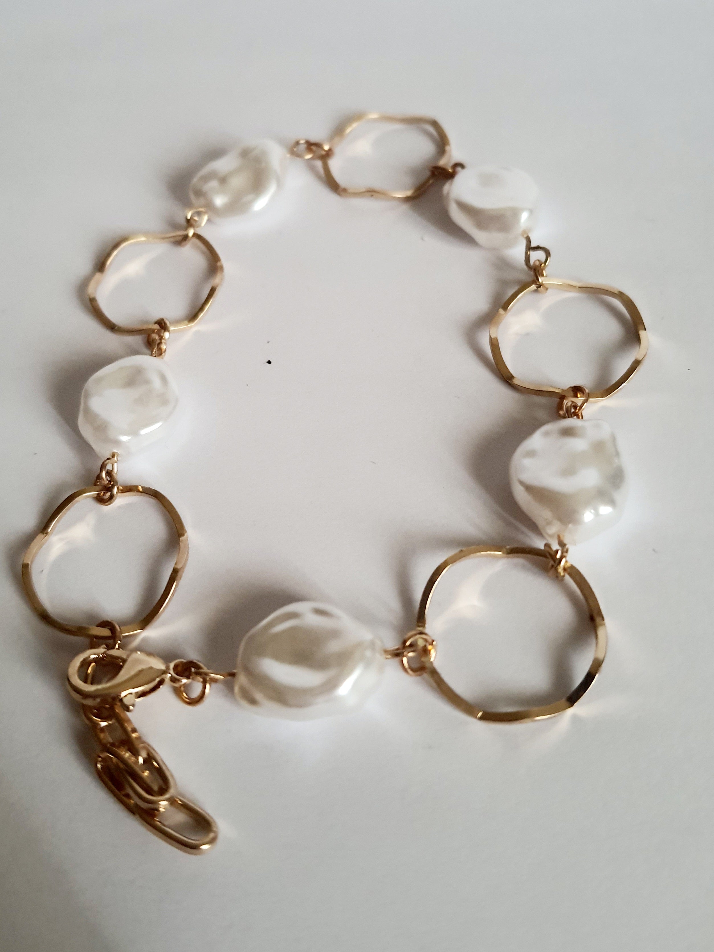 Bransoletka ze stali nierdzewnej w kolorze złota, z nieregularnymi białymi perłami i złotymi kołami. Regulowana długość 22–26 cm. Styl elegancki i minimalistyczny. Rouge Bizu.