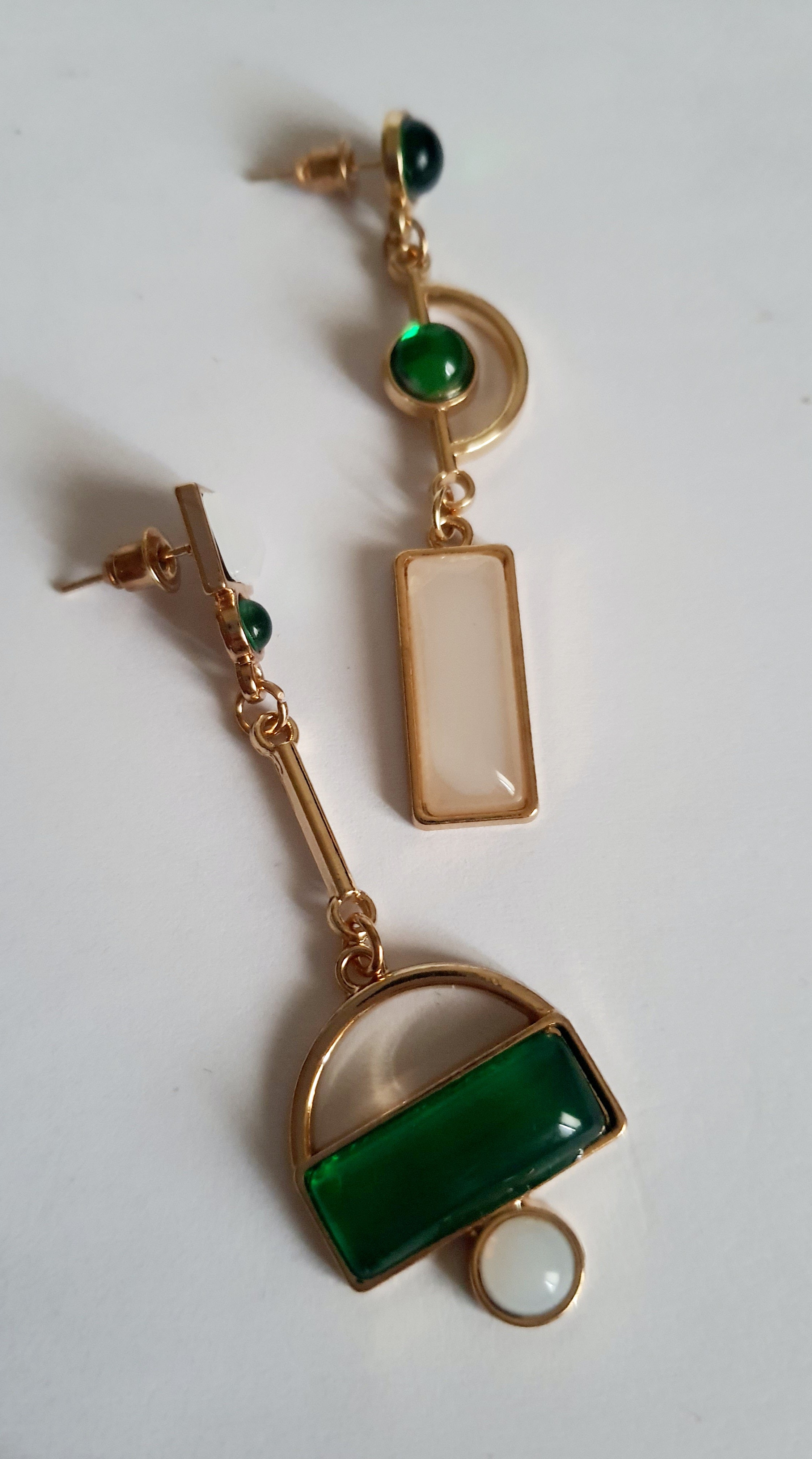 Kolczyki geometryczne ze stali nierdzewnej w kolorze złota, z zielonymi i białymi elementami w różnych kształtach. Asymetryczna forma, długość 6 cm. Styl nowoczesny i elegancki. Rouge Bizu.