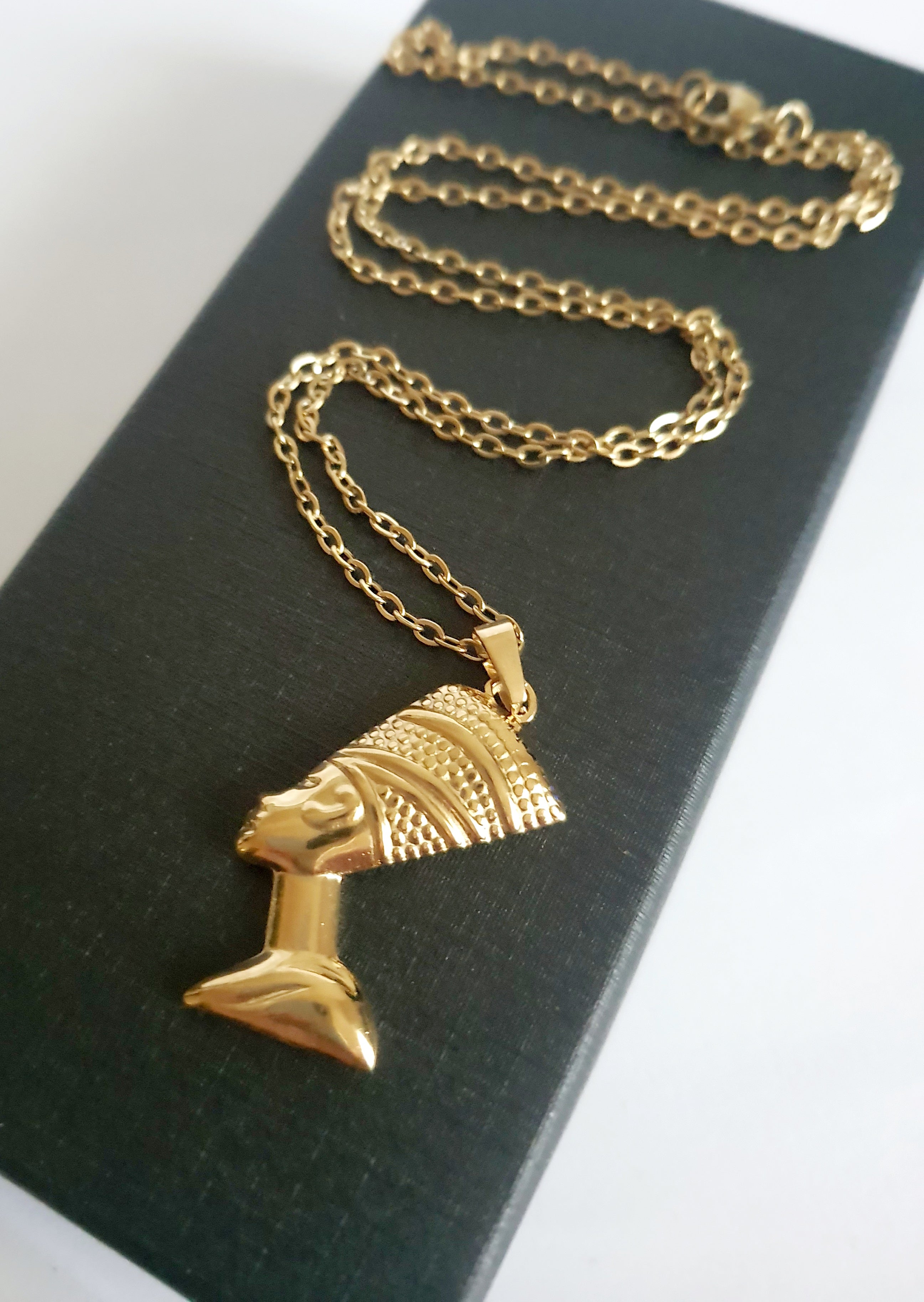 Naszyjnik ze stali nierdzewnej w kolorze złota, z zawieszką przedstawiającą profil królowej w koronie. Długość 50 cm. Styl elegancki i symboliczny. Rouge Bizu.