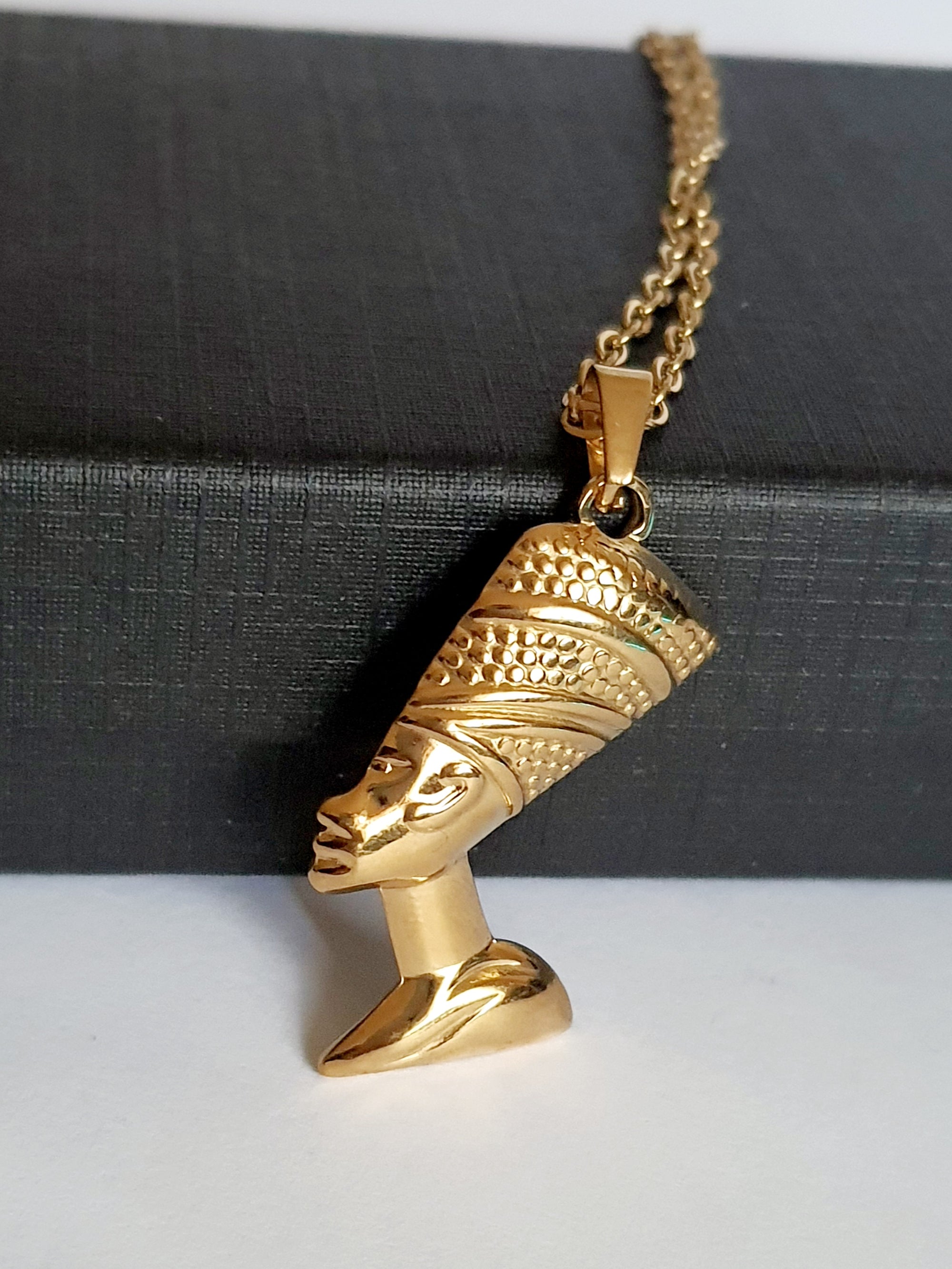 Naszyjnik ze stali nierdzewnej w kolorze złota, z zawieszką przedstawiającą profil królowej w koronie. Długość 50 cm. Styl elegancki i symboliczny. Rouge Bizu.