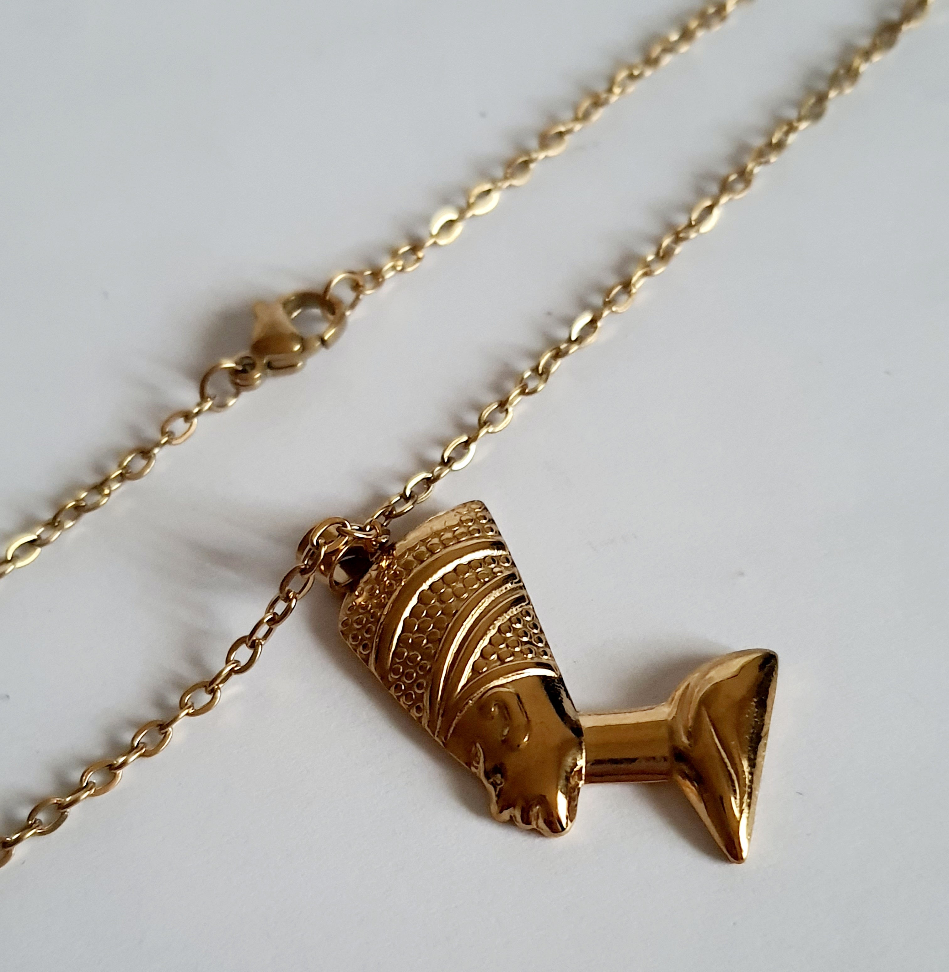 Naszyjnik ze stali nierdzewnej w kolorze złota, z zawieszką przedstawiającą profil królowej w koronie. Długość 50 cm. Styl elegancki i symboliczny. Rouge Bizu.