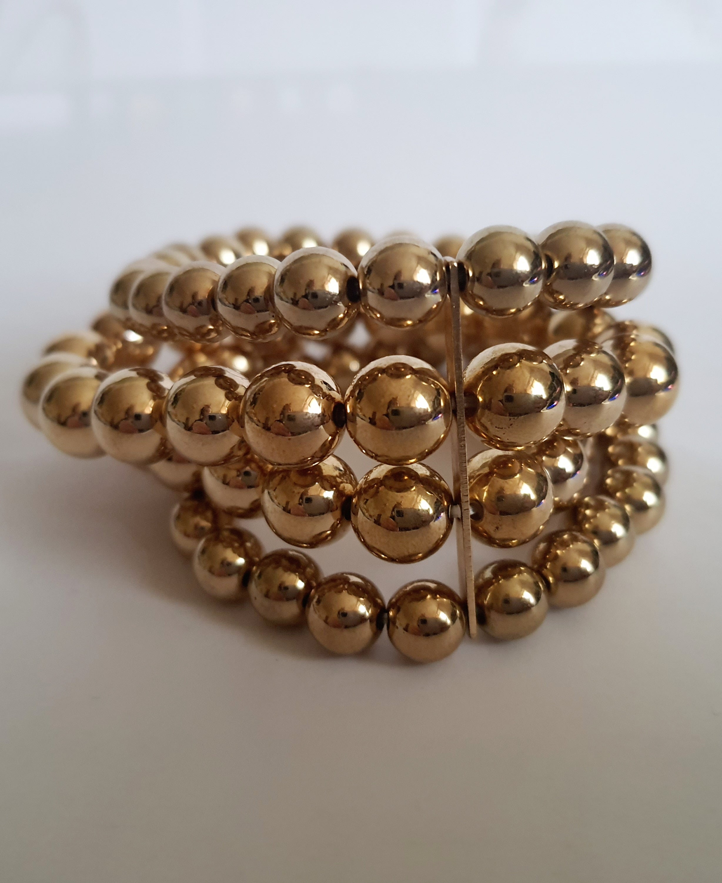 Bransoleta elastyczna na gumce z wielorzędowych złotych koralików, elegancka i klasyczna, Rouge Bizu.