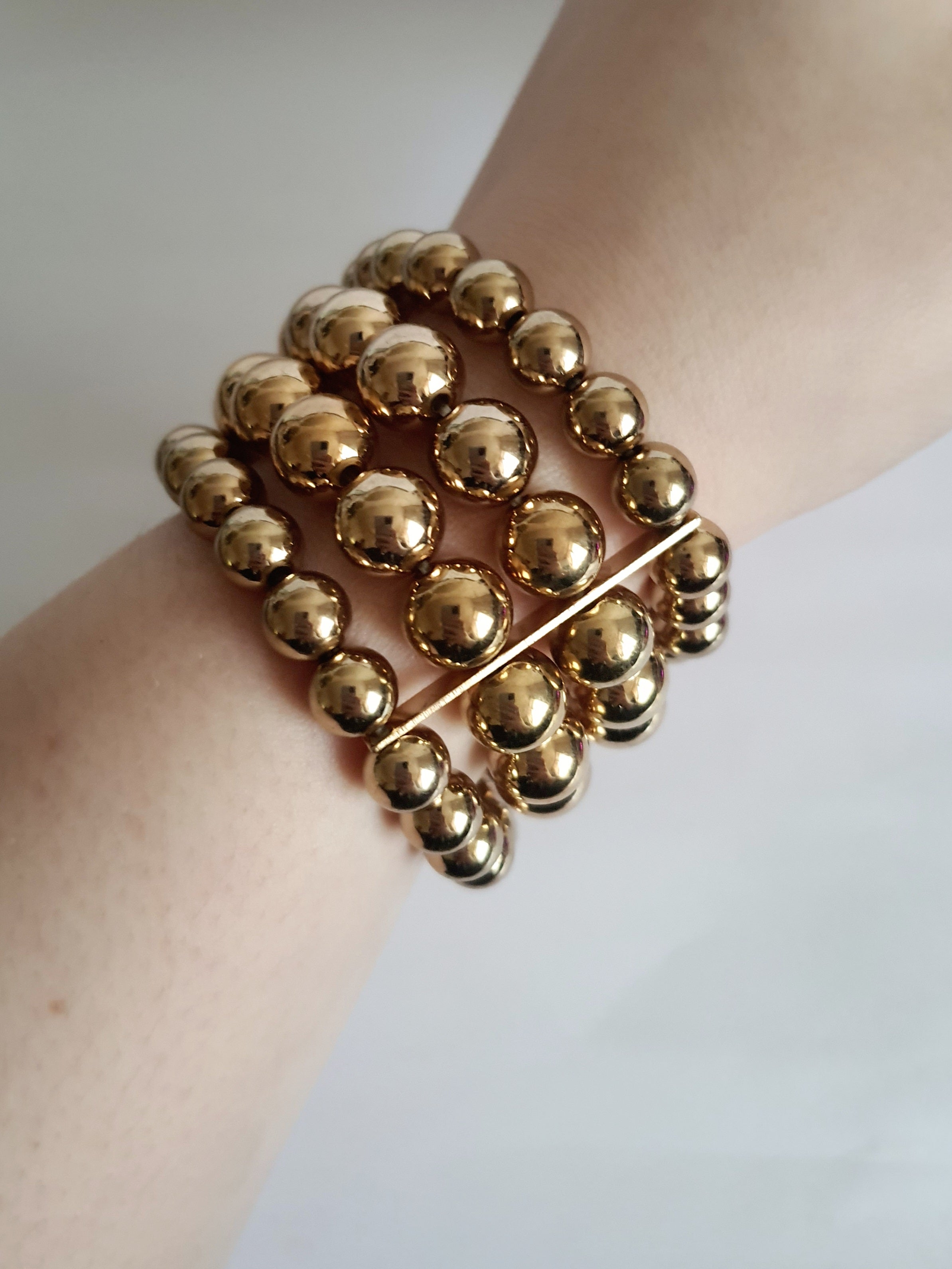 Bransoleta elastyczna na gumce z wielorzędowych złotych koralików, elegancka i klasyczna, Rouge Bizu.