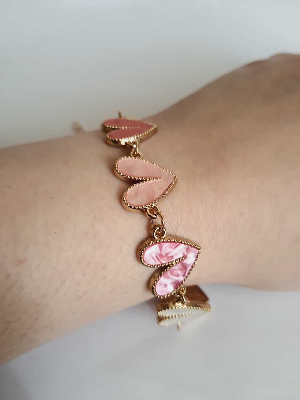 Bransoletka złota 17–22 cm ze stali nierdzewnej, zdobiona kolorowymi sercami w odcieniach różu, bieli i koralu, romantyczna i kobieca, Rouge Bizu. Stal nierdzewna, stal chirurgiczna, hipoalergiczna, nierdzewna, wodoodporna, jakość premium