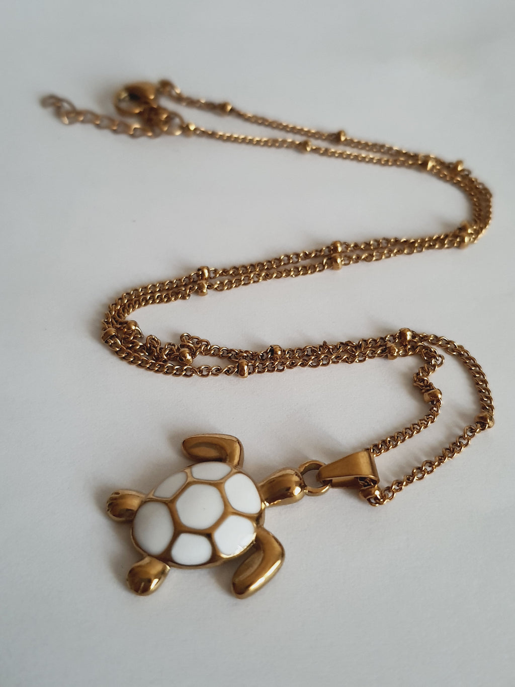 Naszyjnik złoty 40–45 cm ze stali nierdzewnej, zawieszka żółw z białą emalią na pancerzu, symboliczna i elegancka biżuteria, Rouge Bizu.#bizuteria #biżuteriapozłacana #stalnierdzewna #stalchirurgiczna #platerowane18k #wodoodporne #hipoalergiczne #retro #vintage #złotynaszyjnik #rougebizu